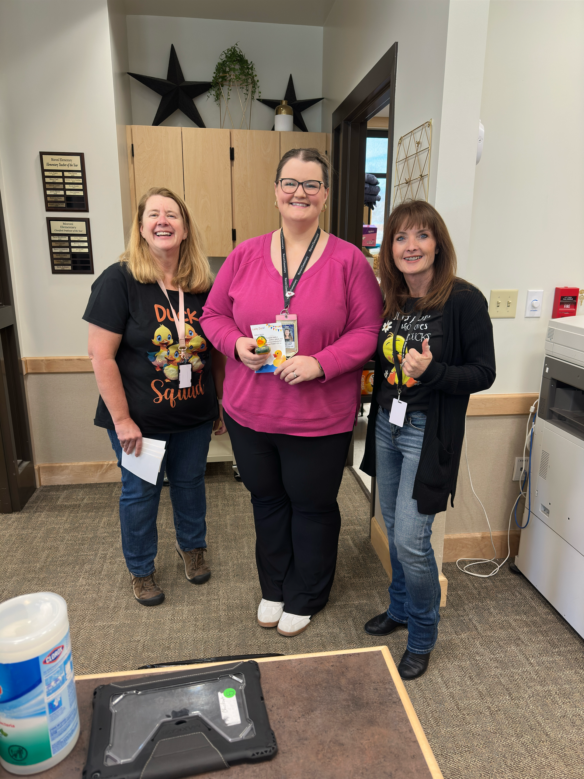 Three women are standing next to each other in a room.