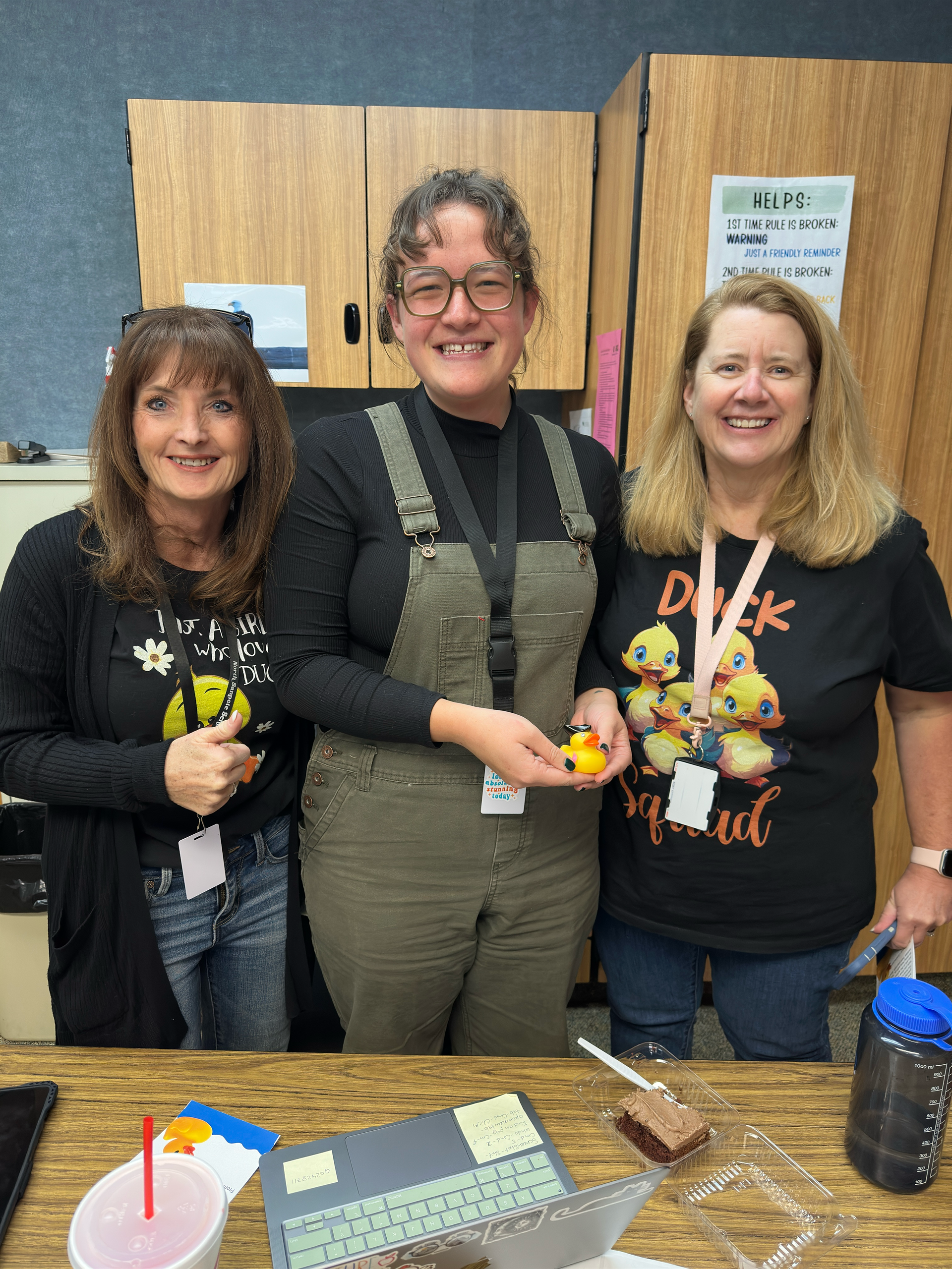 Three women are posing for a picture in a kitchen.