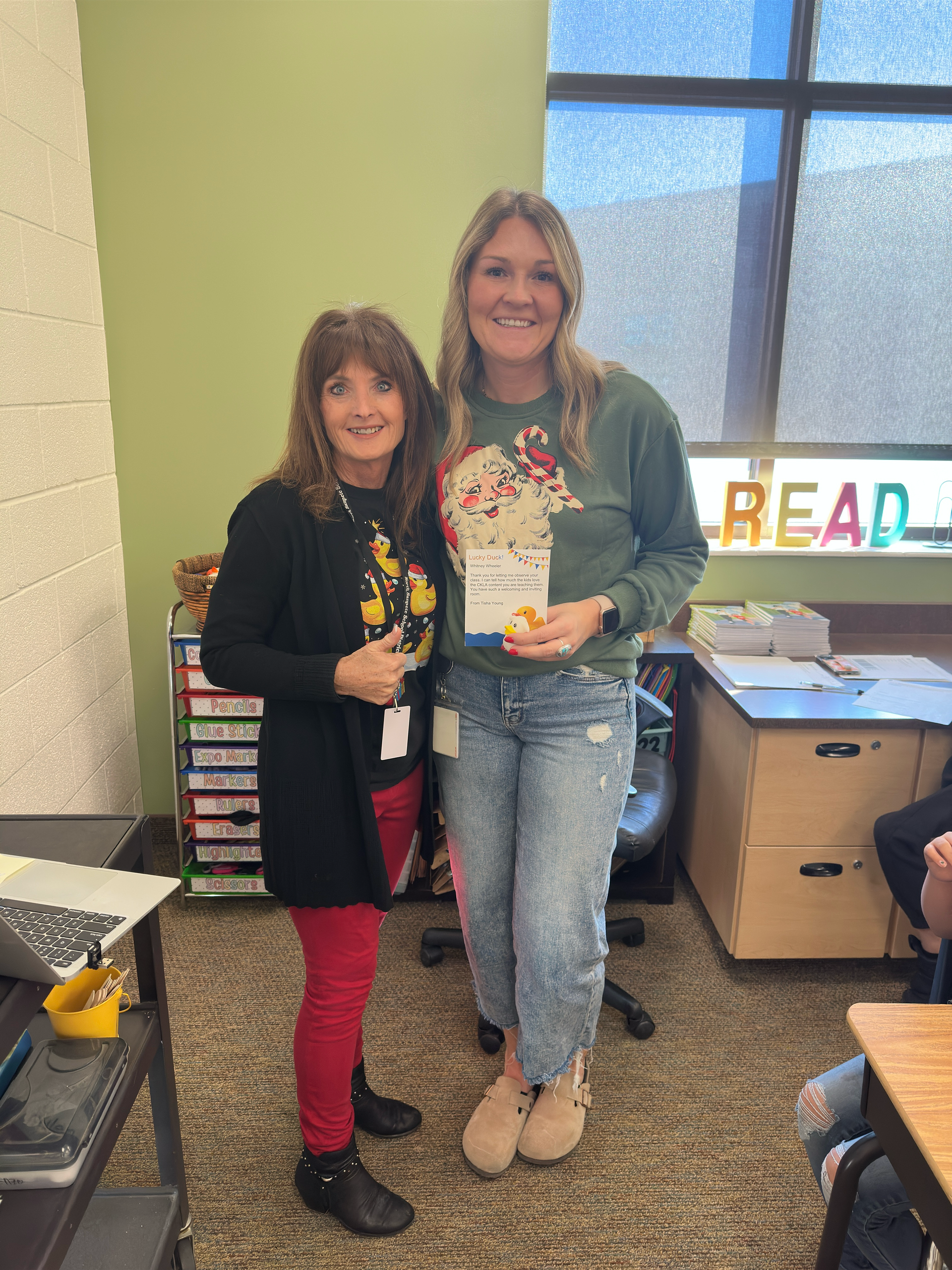 Two women are standing next to each other in a classroom.