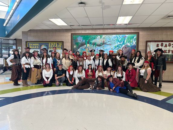 Group of people in pirate costumes posing together indoors.