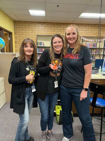 Three women are posing for a picture in a library.