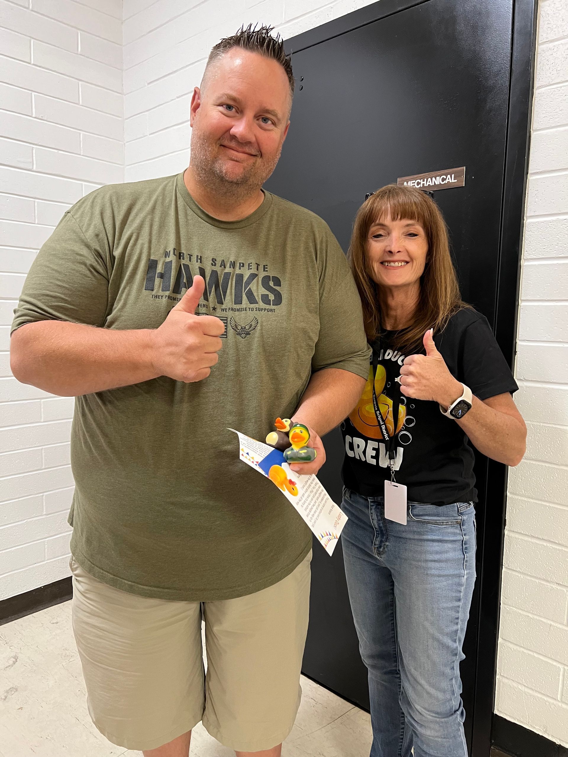 A man and a woman are standing next to each other and giving a thumbs up.