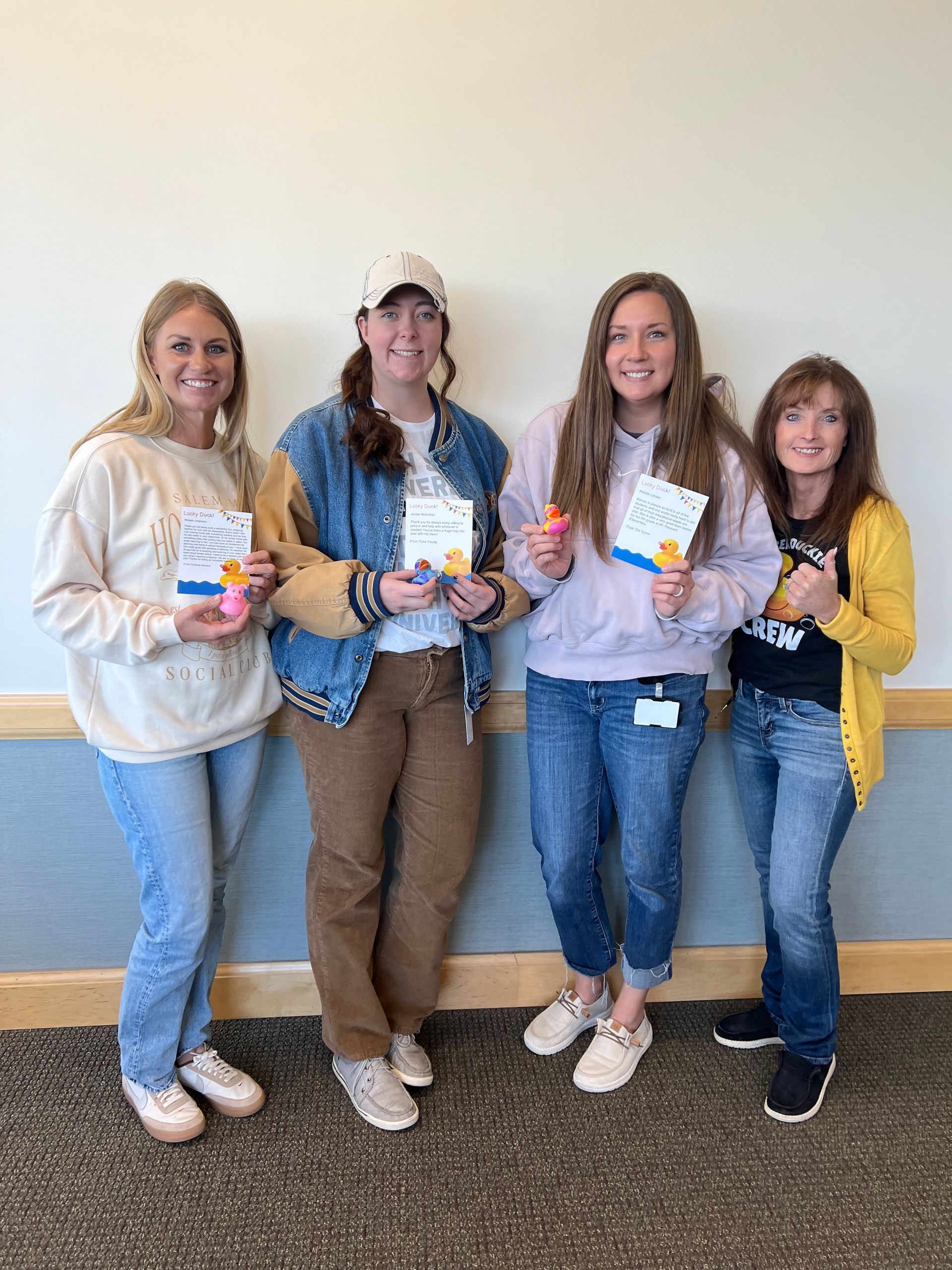 A group of four women are standing next to each other holding cards.