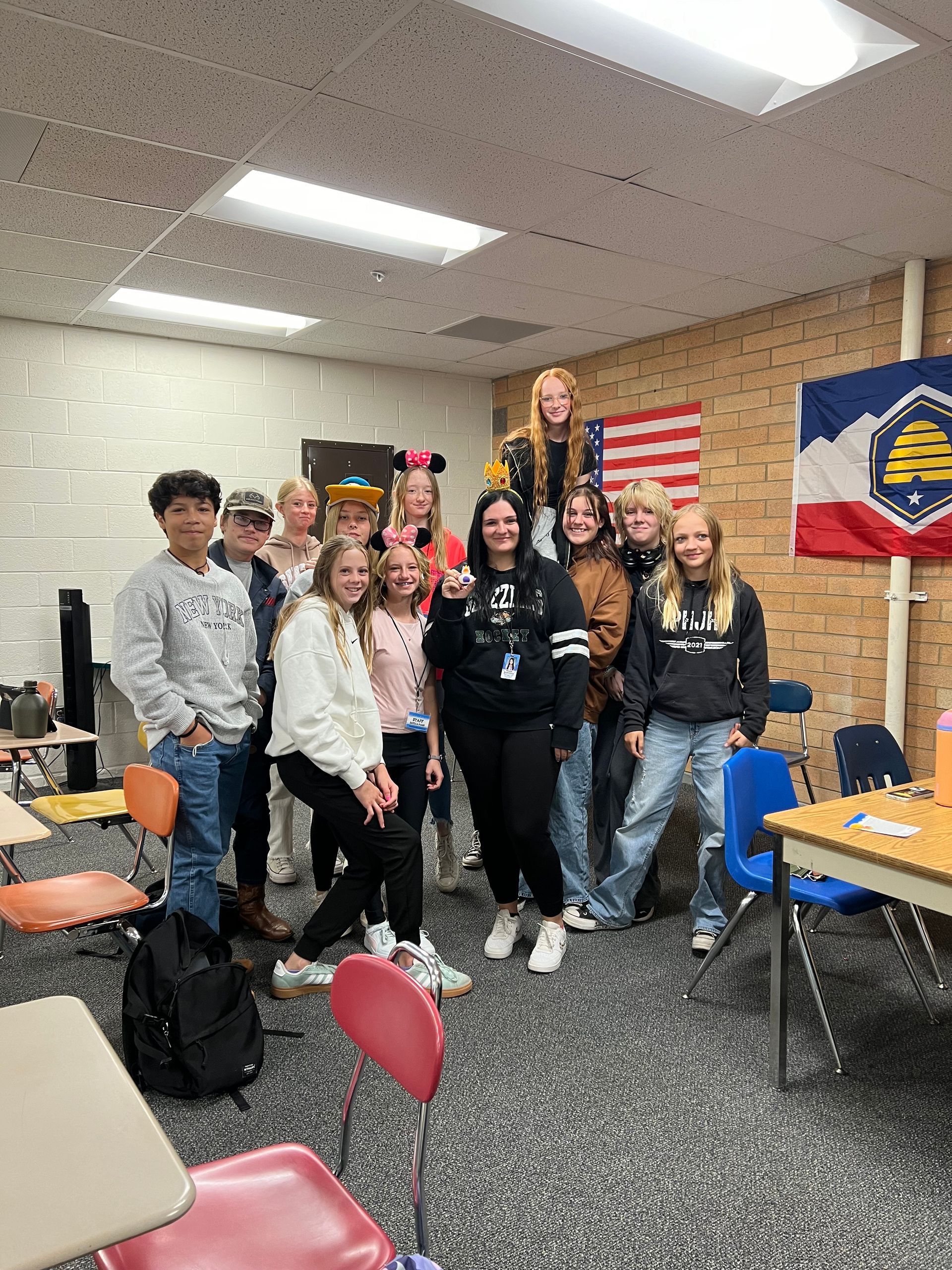 A group of young people are posing for a picture in a classroom.