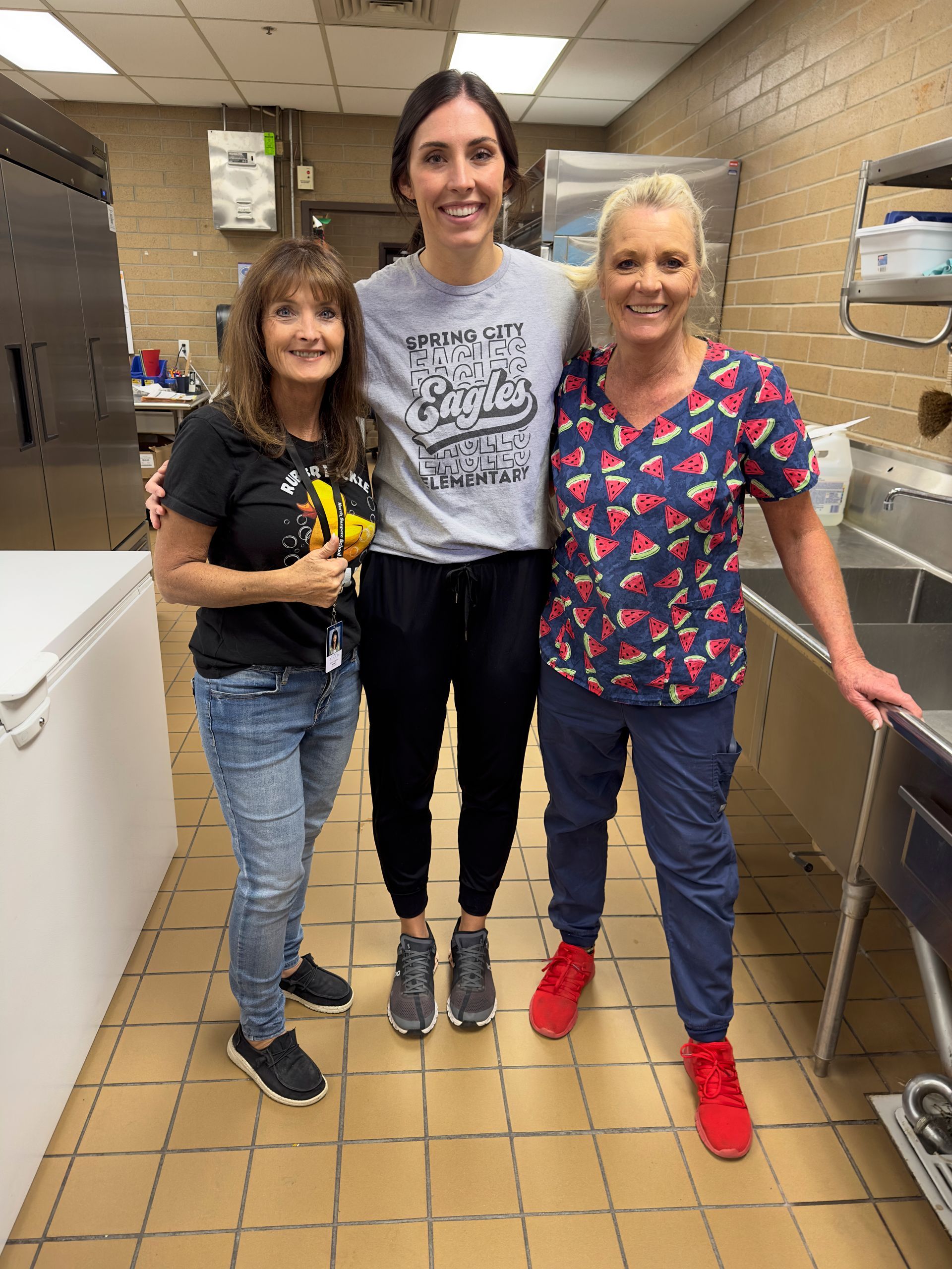 Three women are posing for a picture in a kitchen.