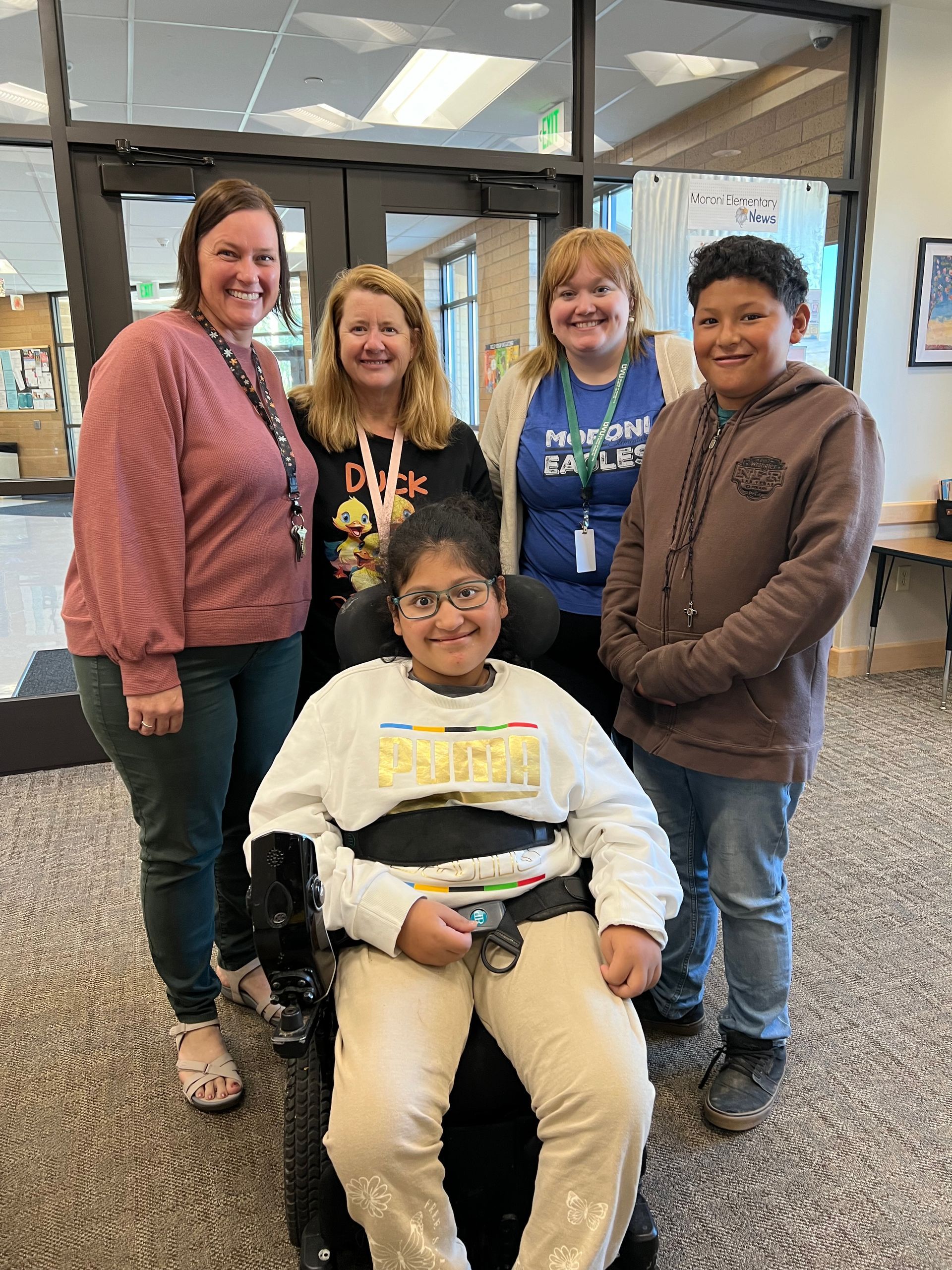 A group of people are posing for a picture with a boy in a wheelchair.