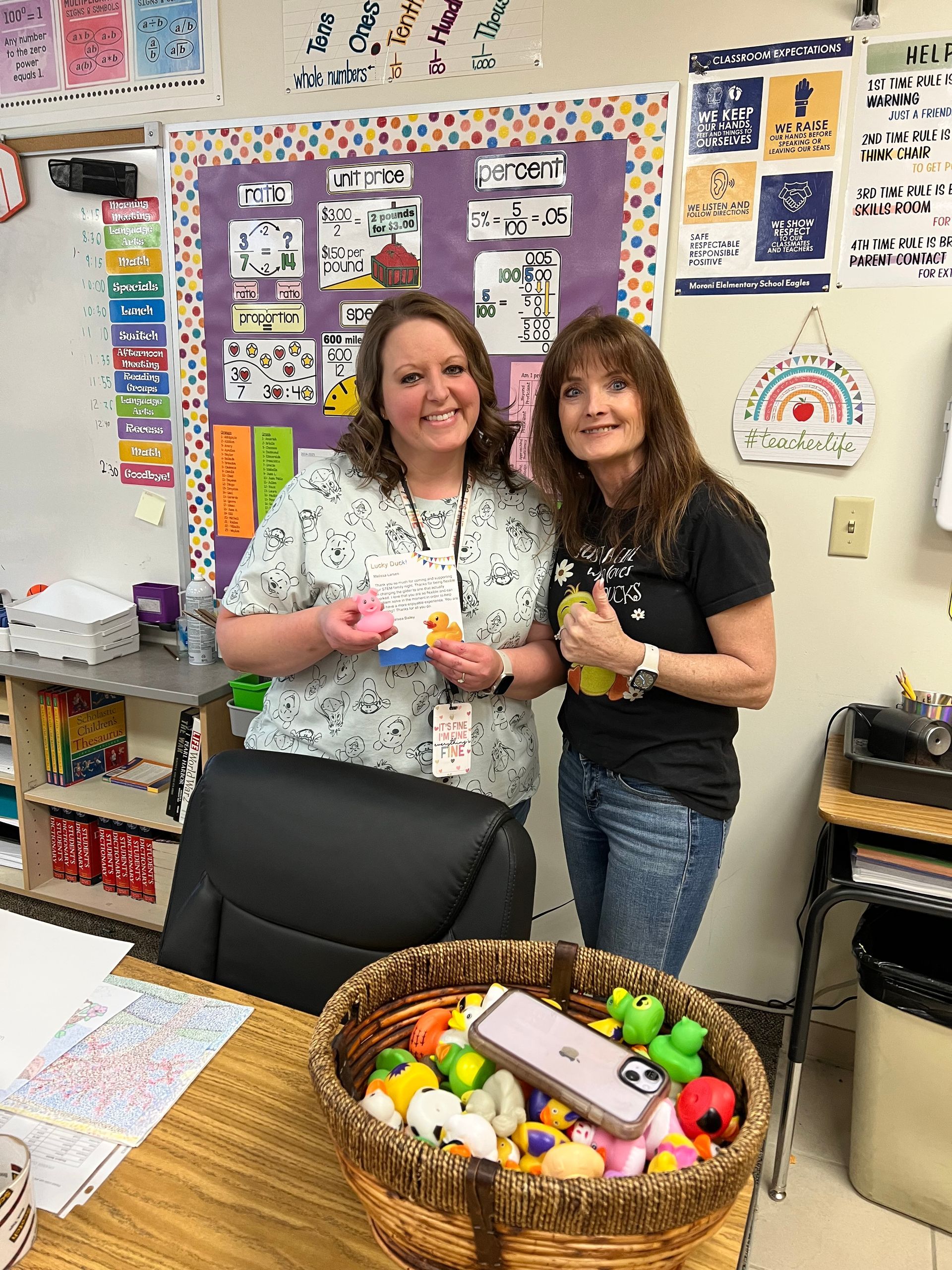 Two women are standing next to each other in a classroom holding toys.