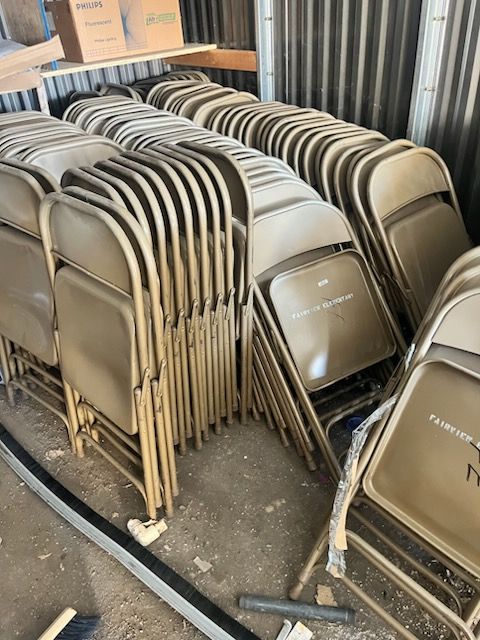 A bunch of folding chairs are stacked on top of each other in a warehouse.