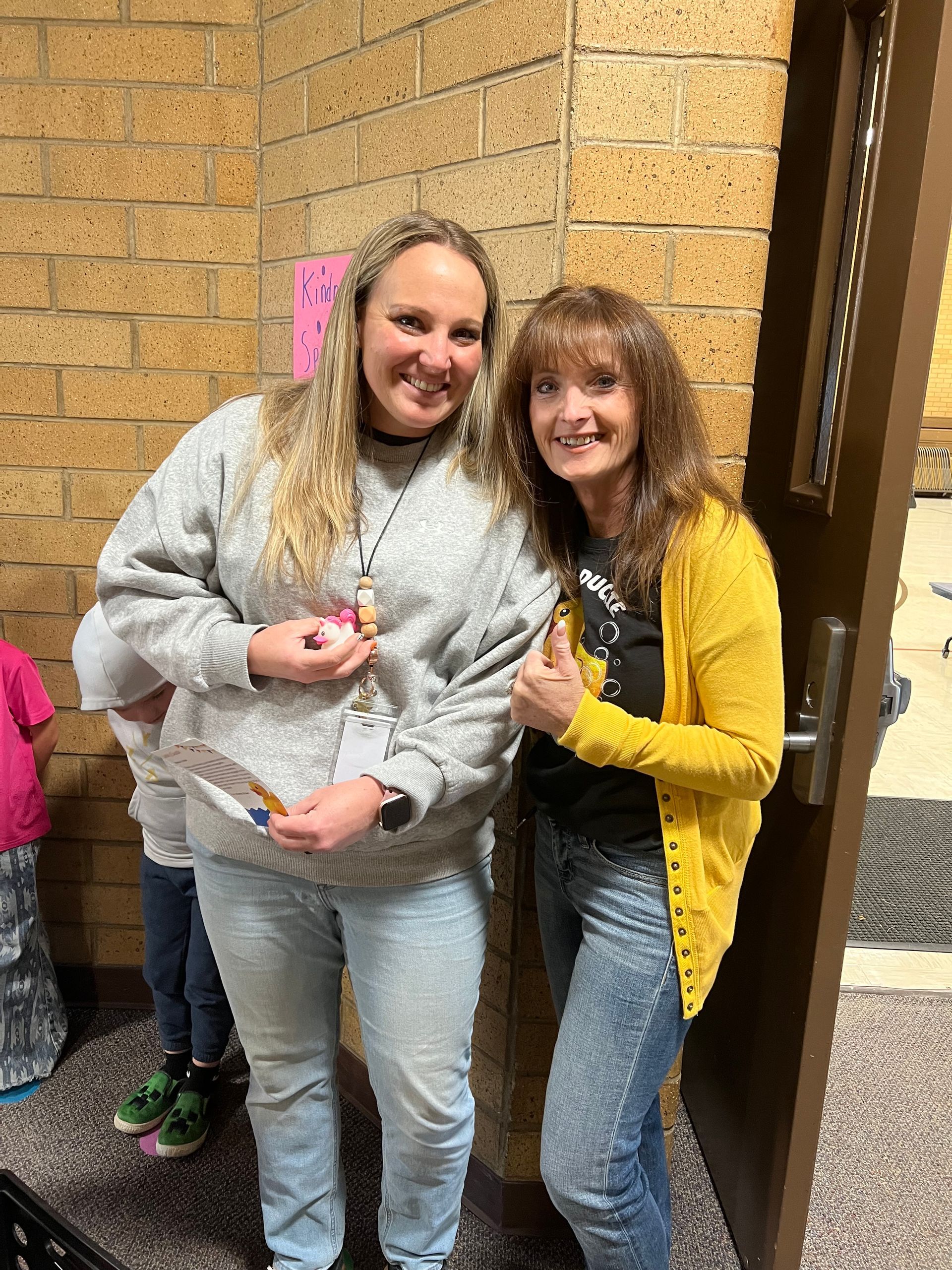 Two women are standing next to each other in front of a door.