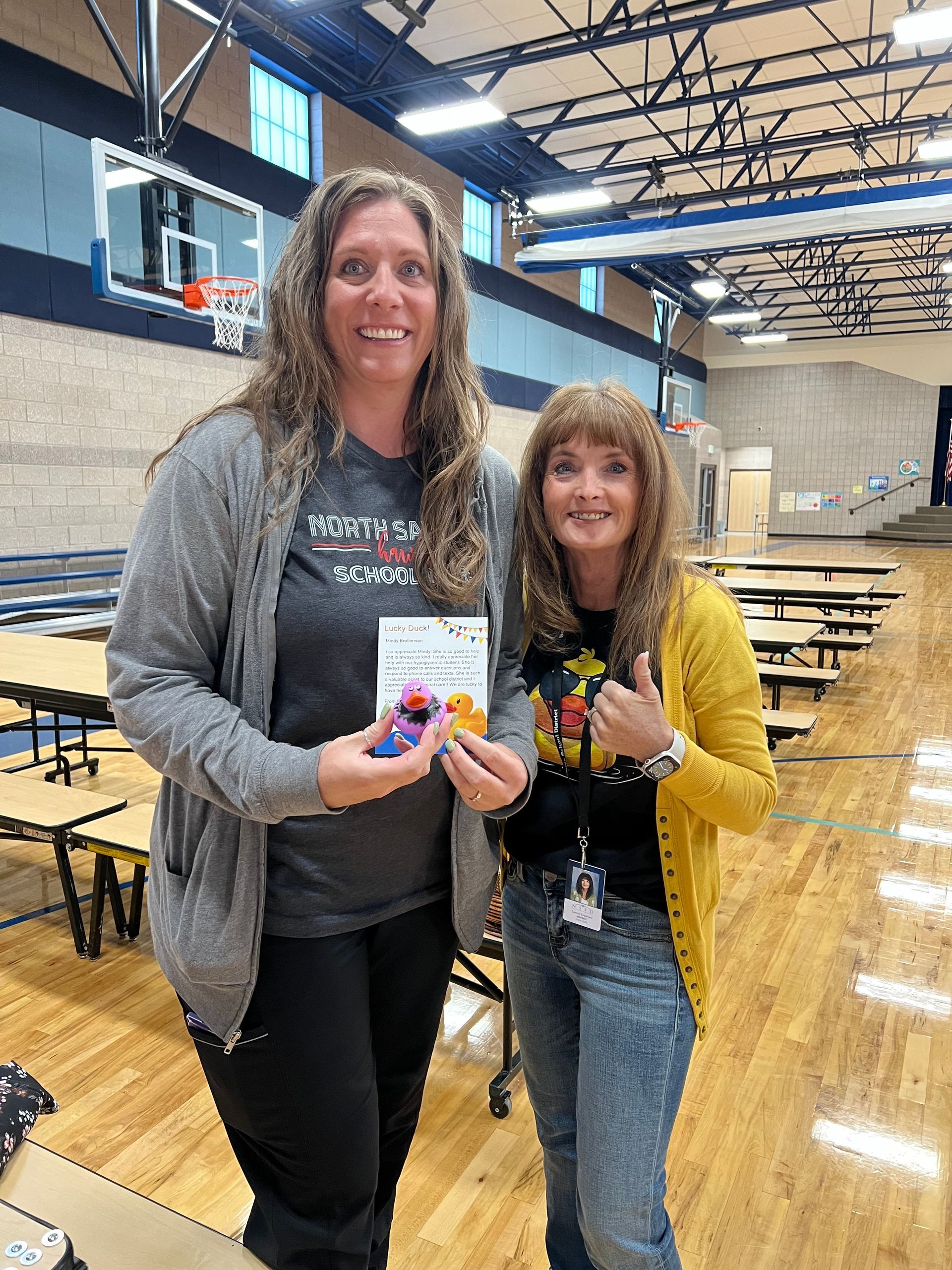 Two women are standing next to each other in a gym.