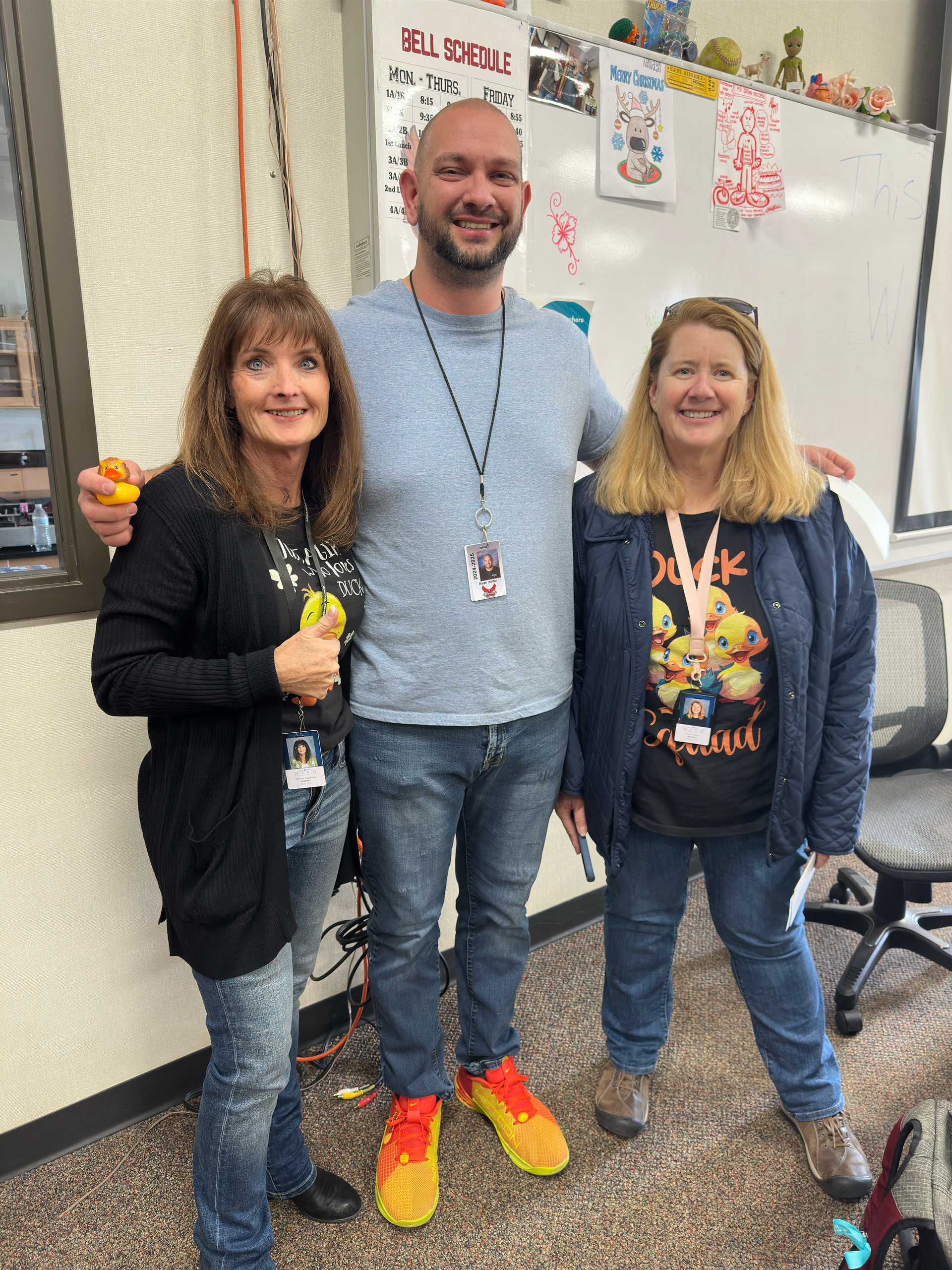 A man and two women are posing for a picture in a classroom.