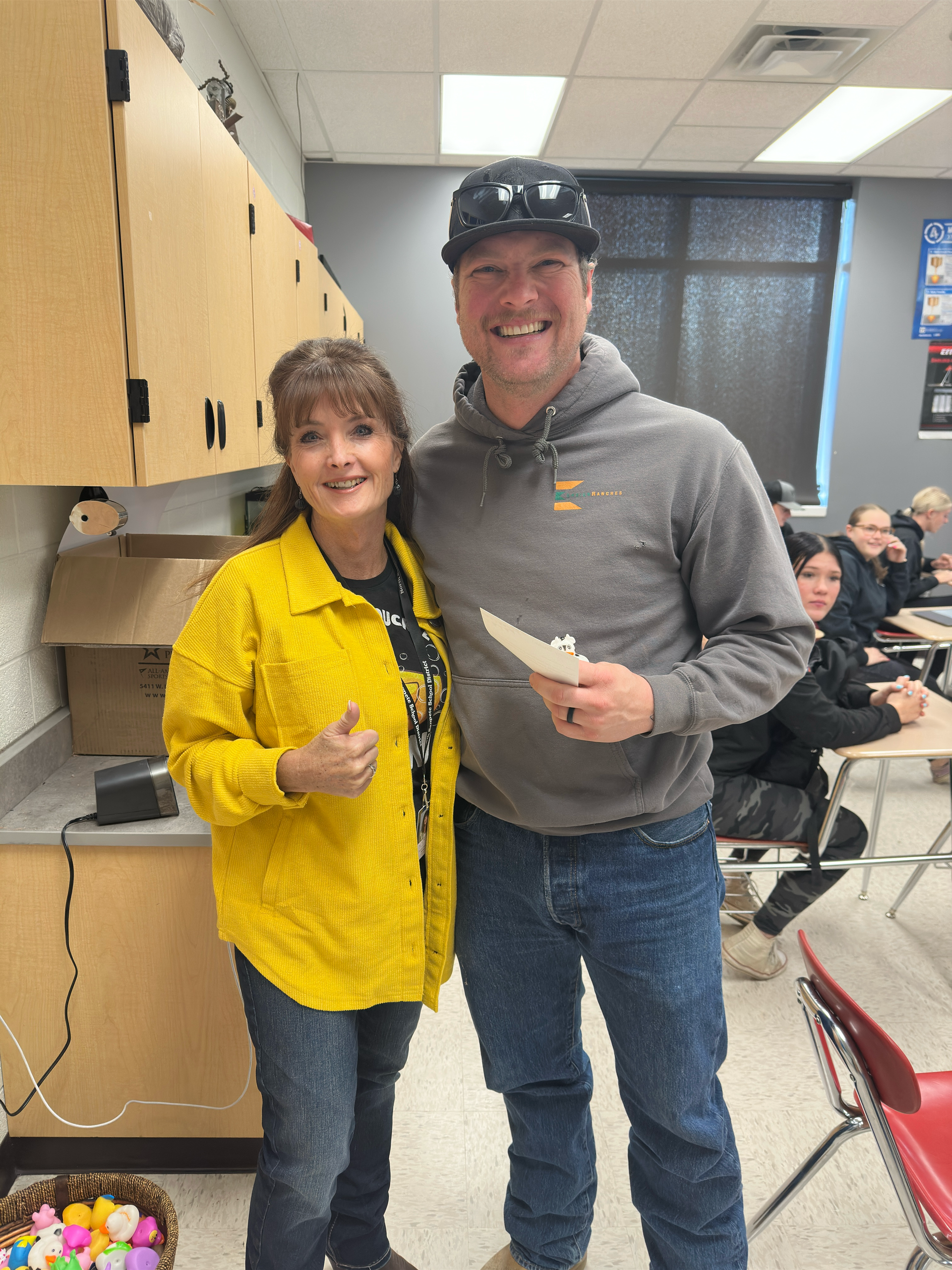 A man and a woman are posing for a picture in a classroom