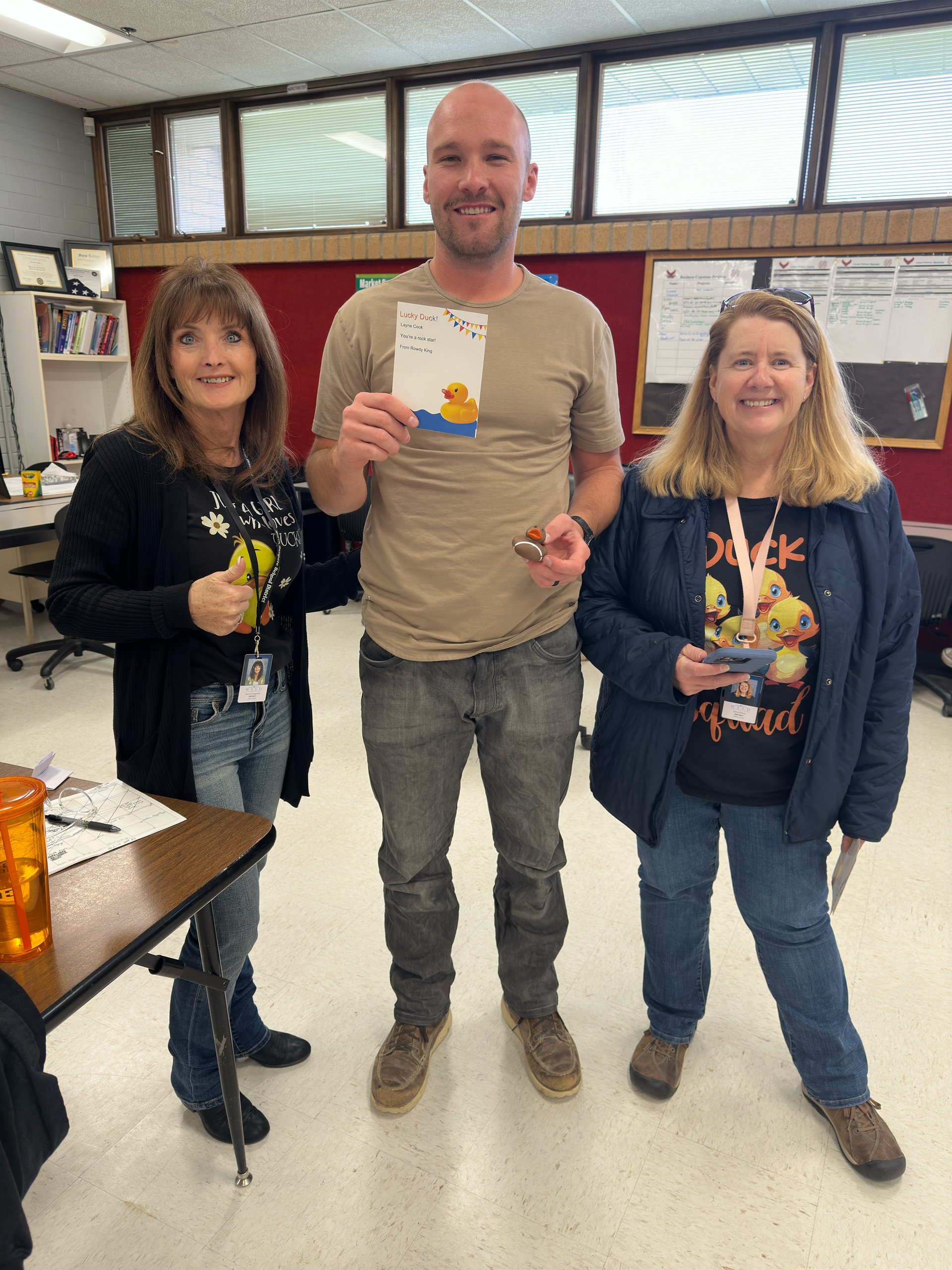 A man and two women are standing next to each other in a room.