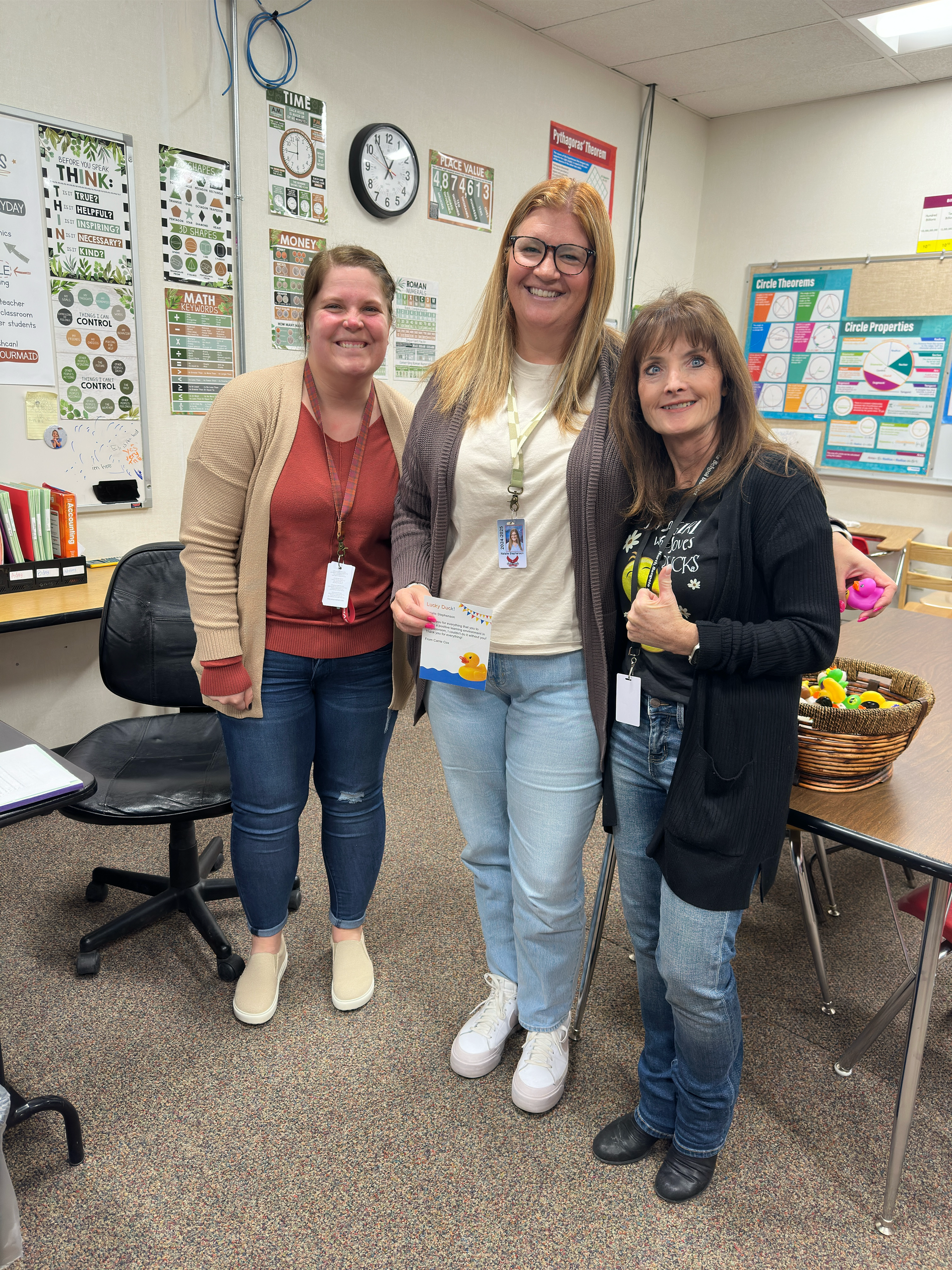 Three women are posing for a picture in a classroom.