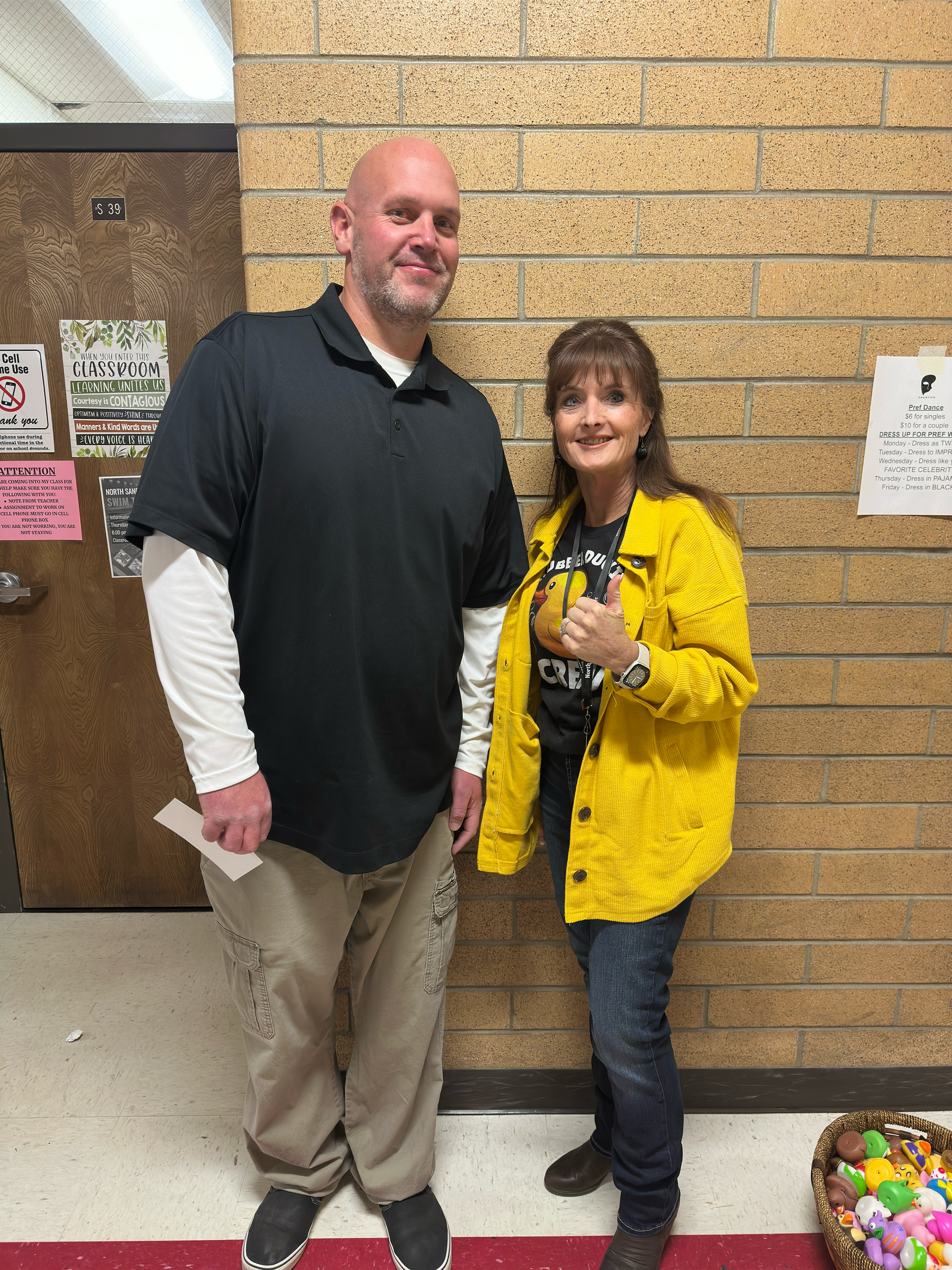 A man and a woman are standing next to each other in front of a brick wall.