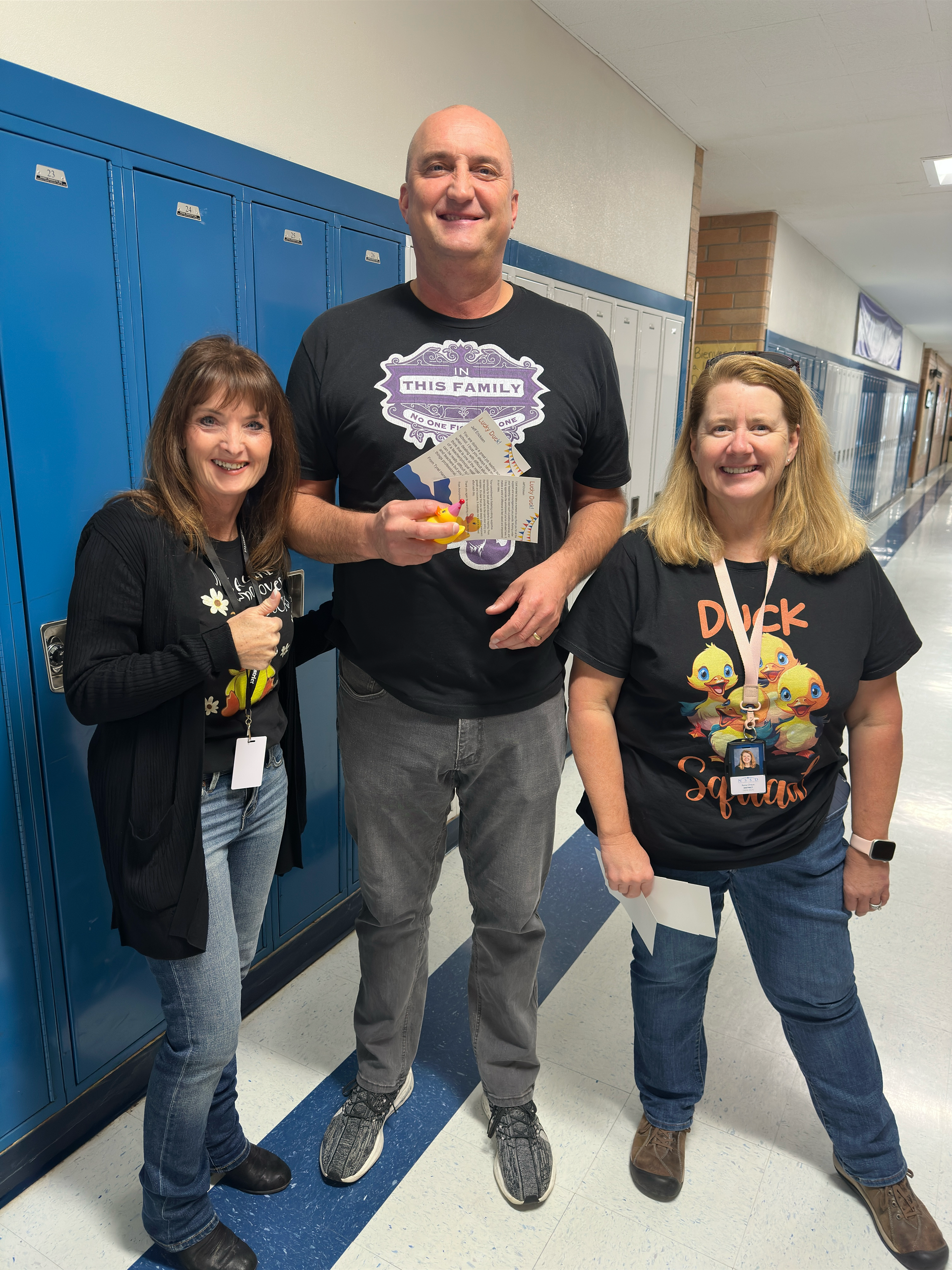 A man and two women are standing next to each other in a hallway.