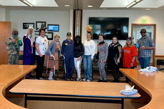 Group of people in costumes posing in a meeting room with a large table.