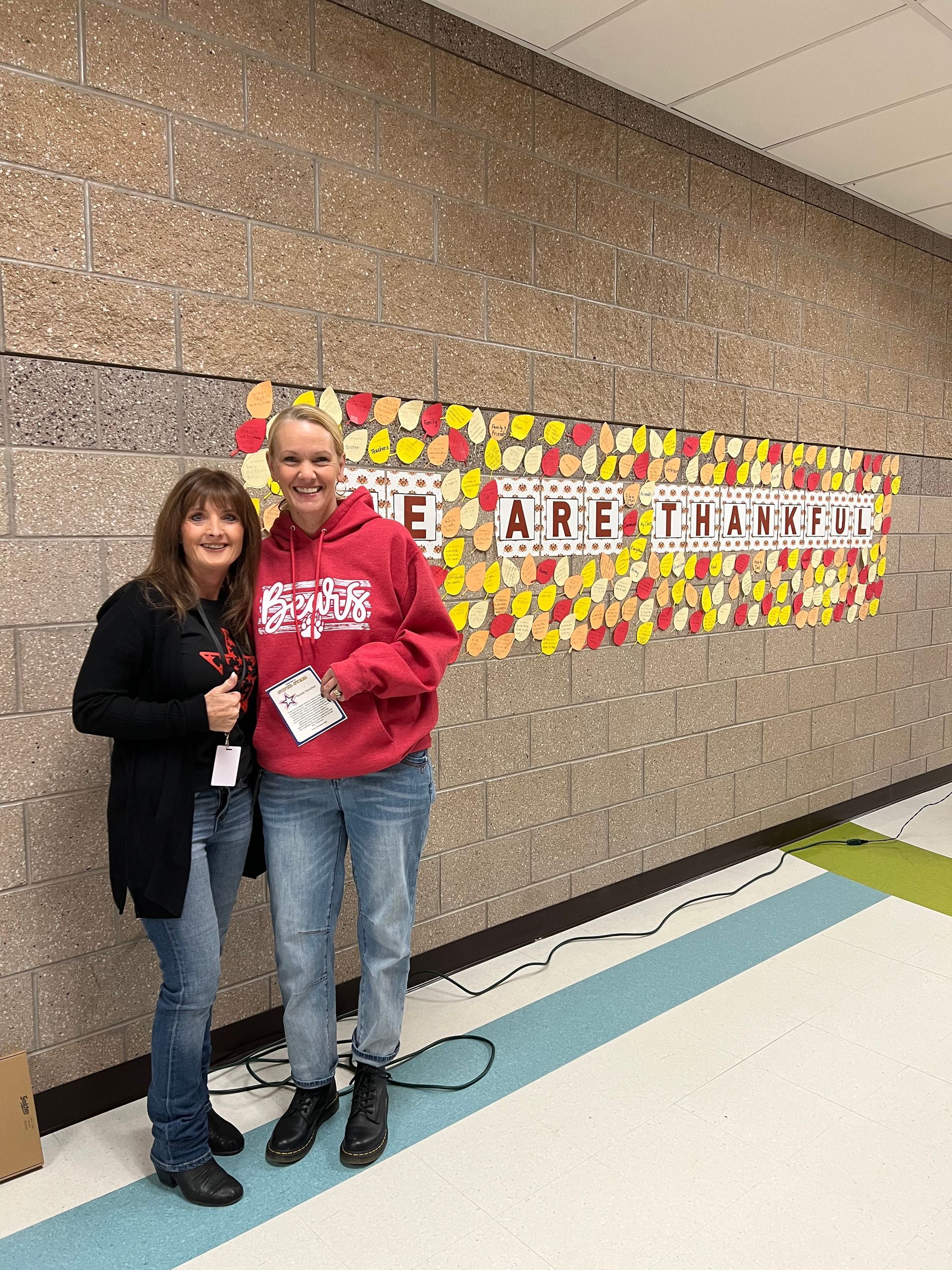 Two women stand by a wall display that says 