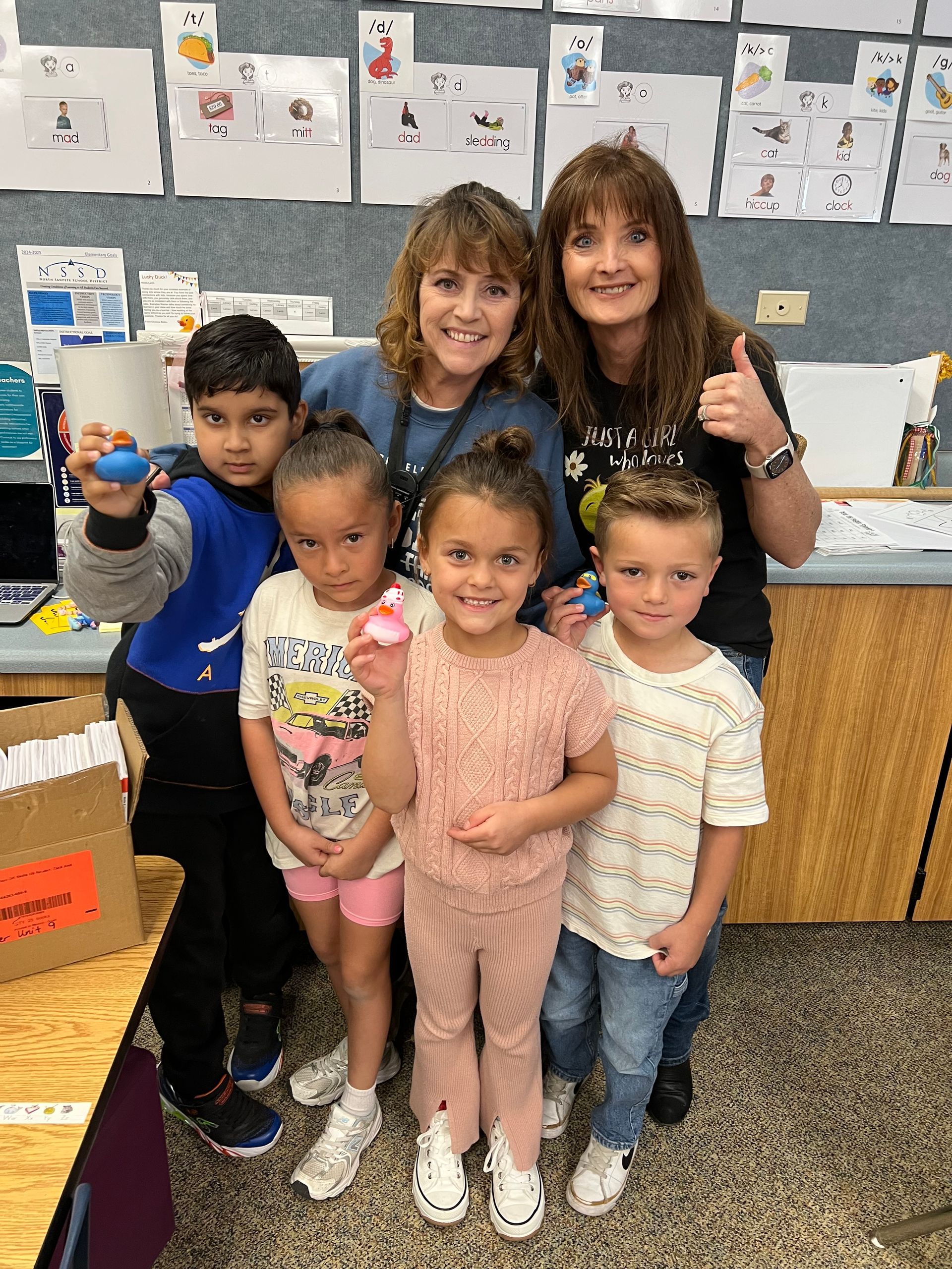 A group of children and a teacher are posing for a picture in a classroom.