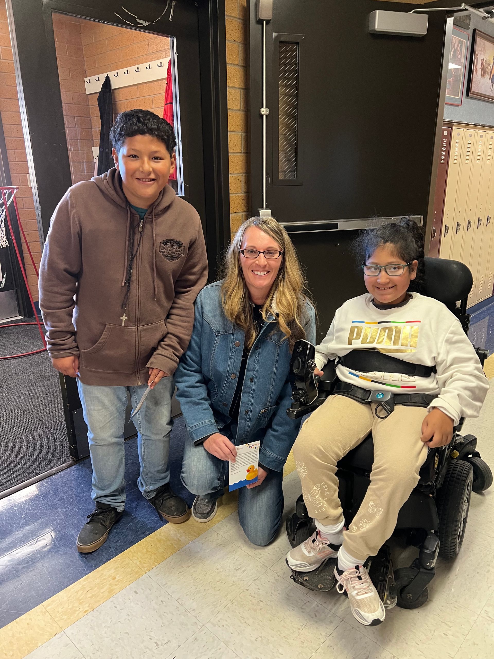 A woman and two children are posing for a picture in a hallway . one of the children is in a wheelchair.