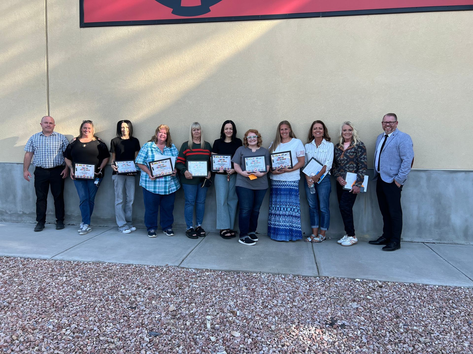 A group of people standing in front of a building holding certificates.