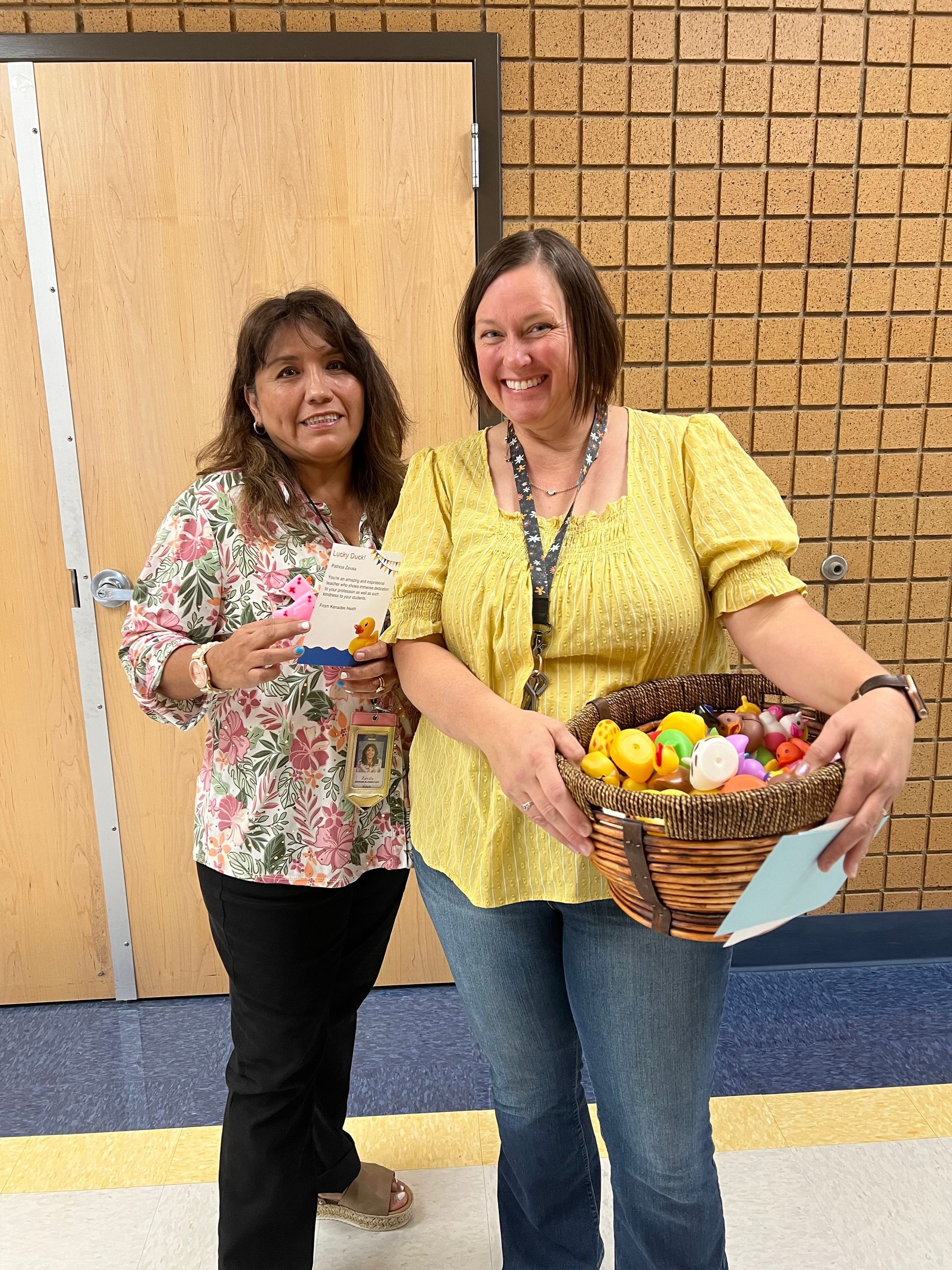 Two women are standing next to each other holding a basket of easter eggs.