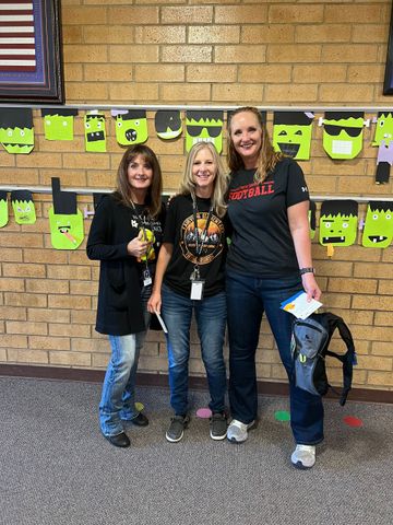 Three women are posing for a picture in front of a brick wall.