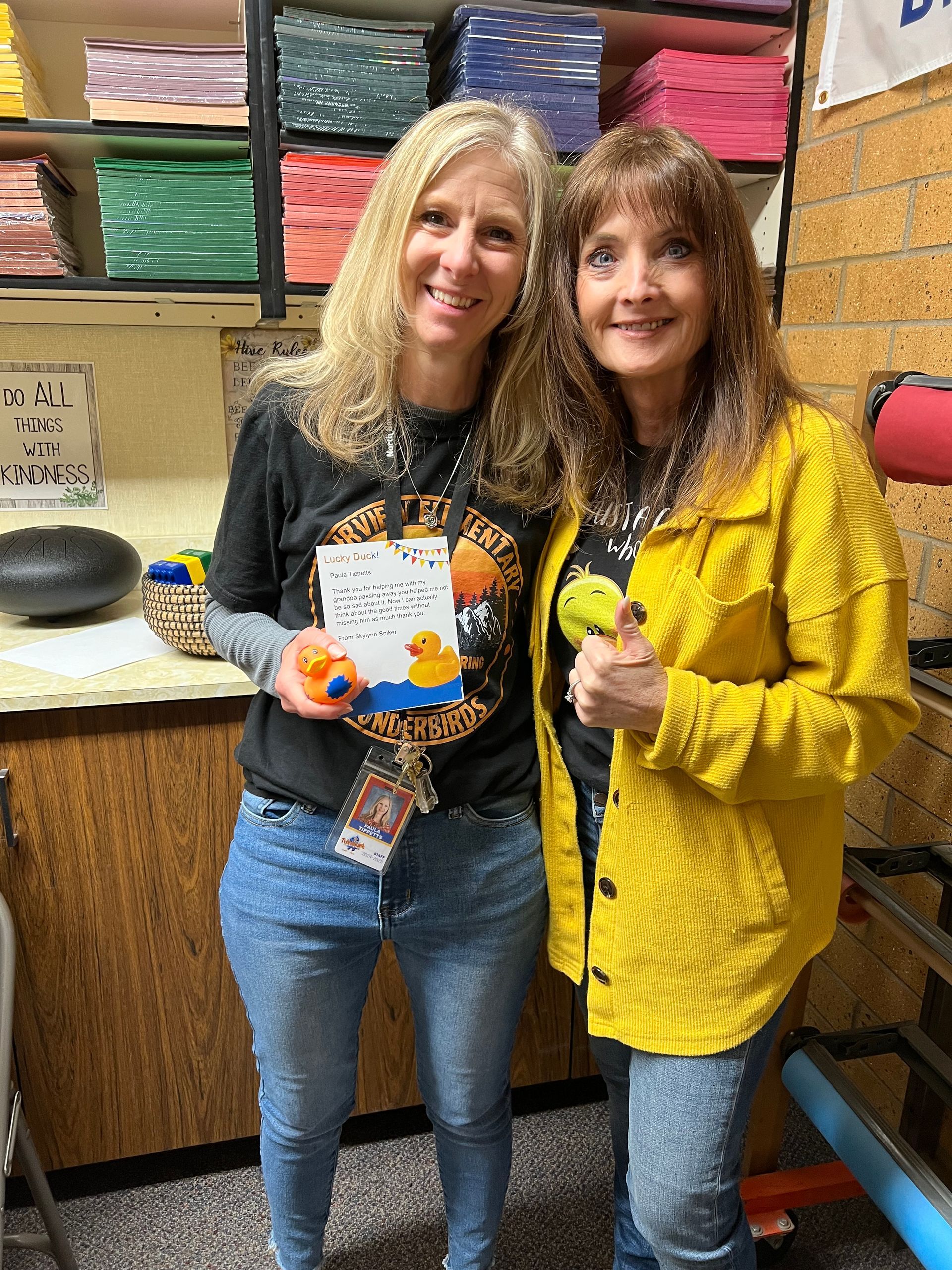 Two women are standing next to each other in a room holding rubber ducks.