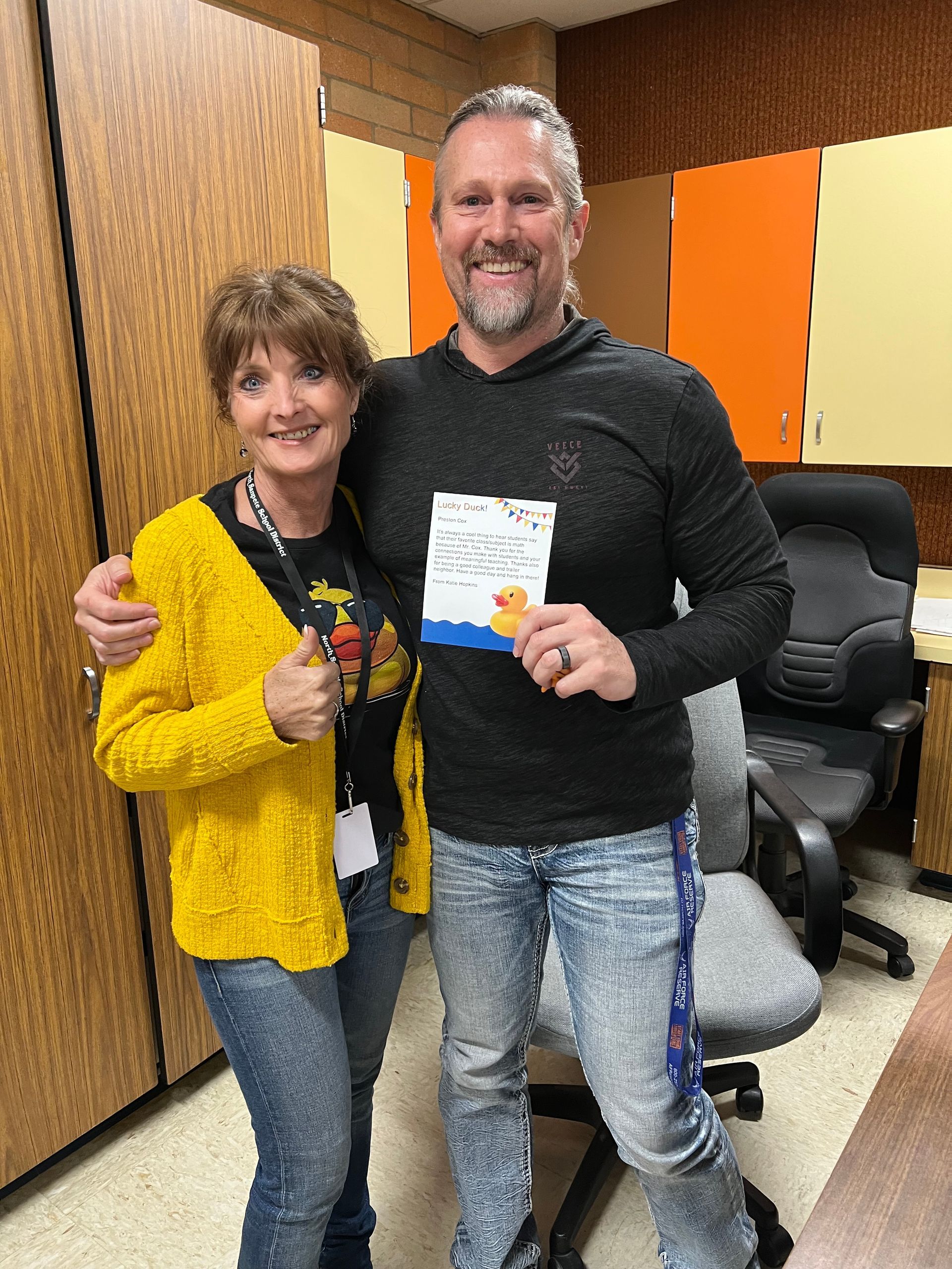 A man and a woman are posing for a picture in an office . the man is holding a certificate.