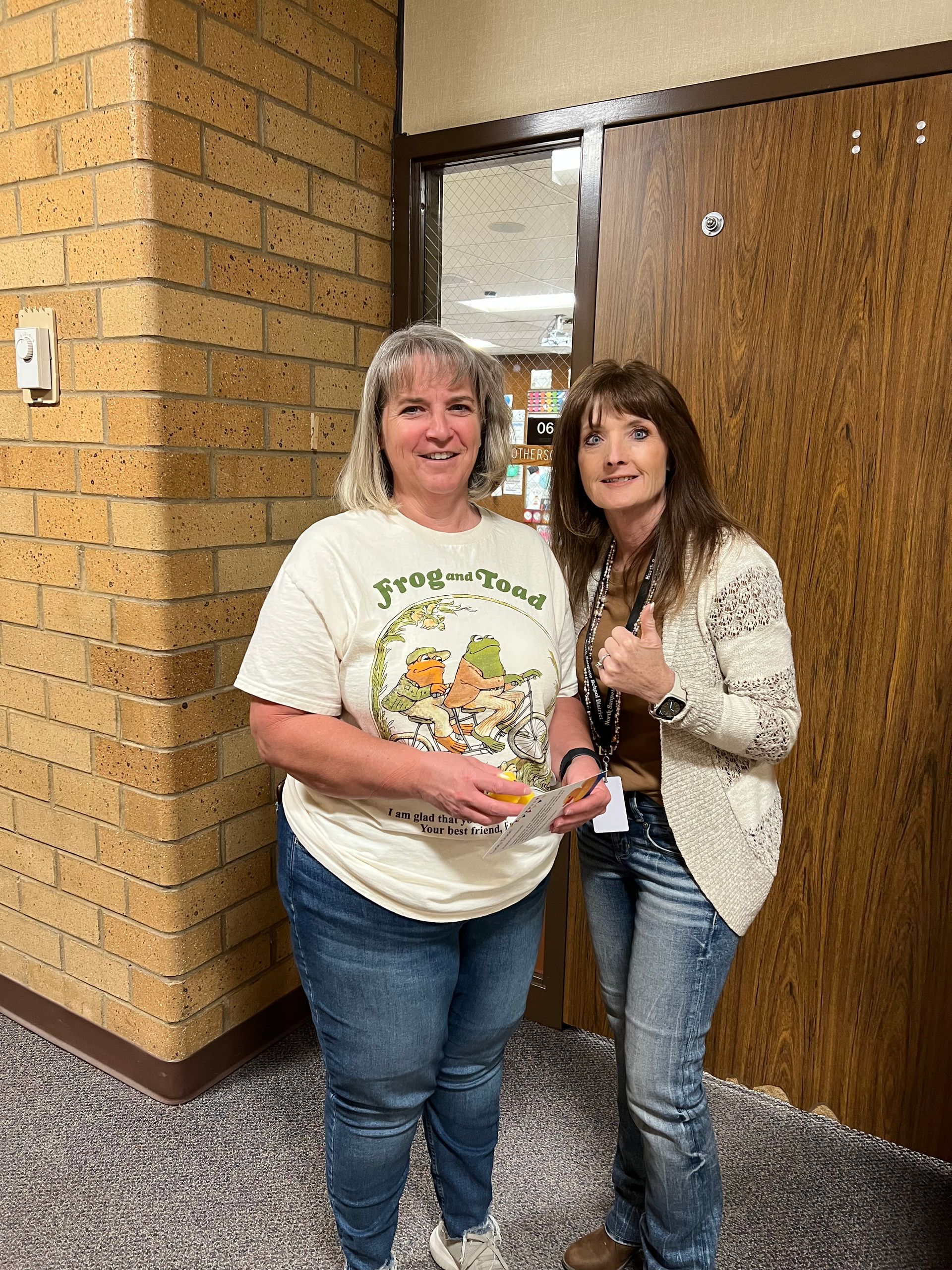 Two women are standing next to each other in a hallway.