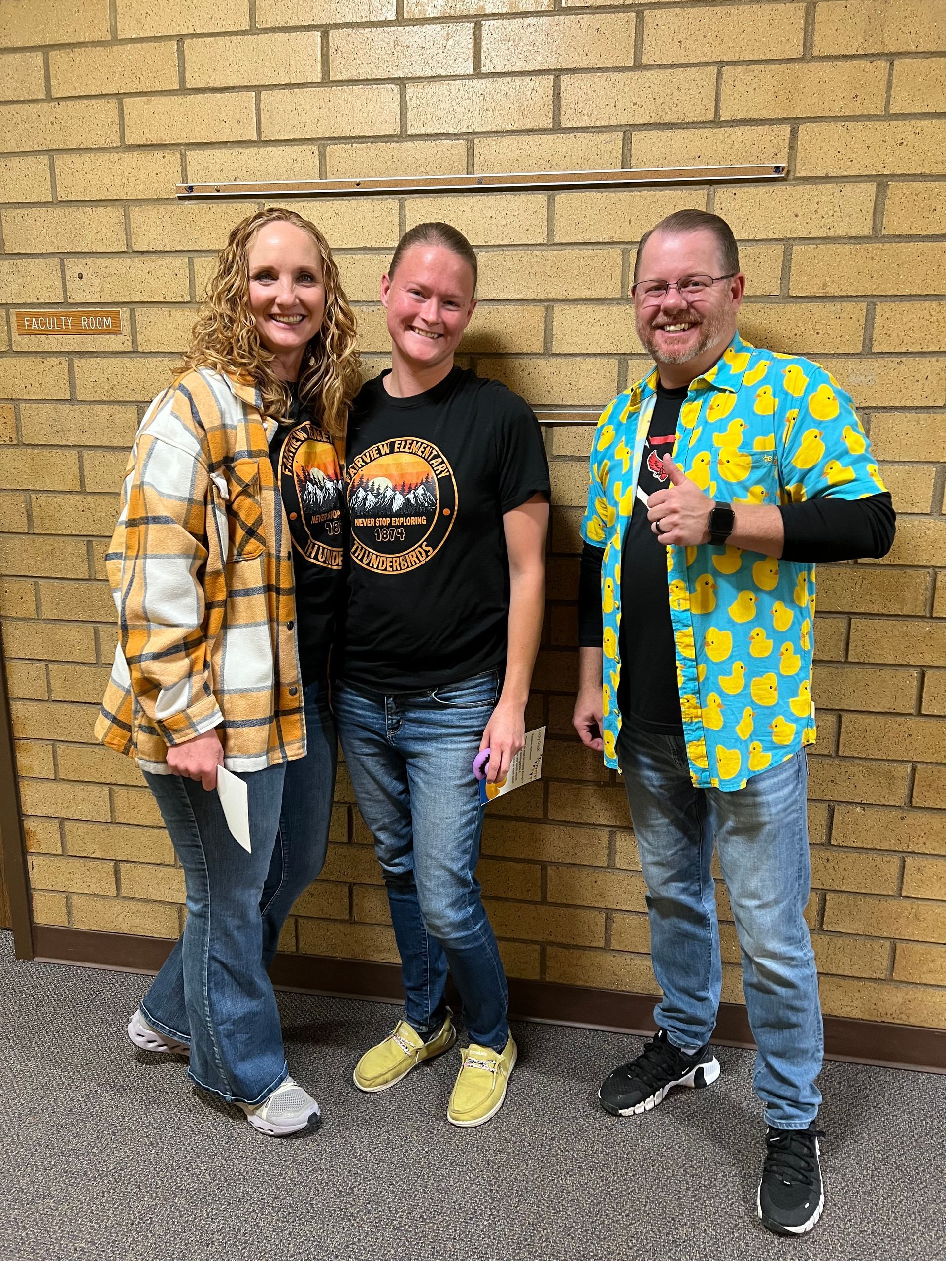 Three people are posing for a picture in front of a brick wall.