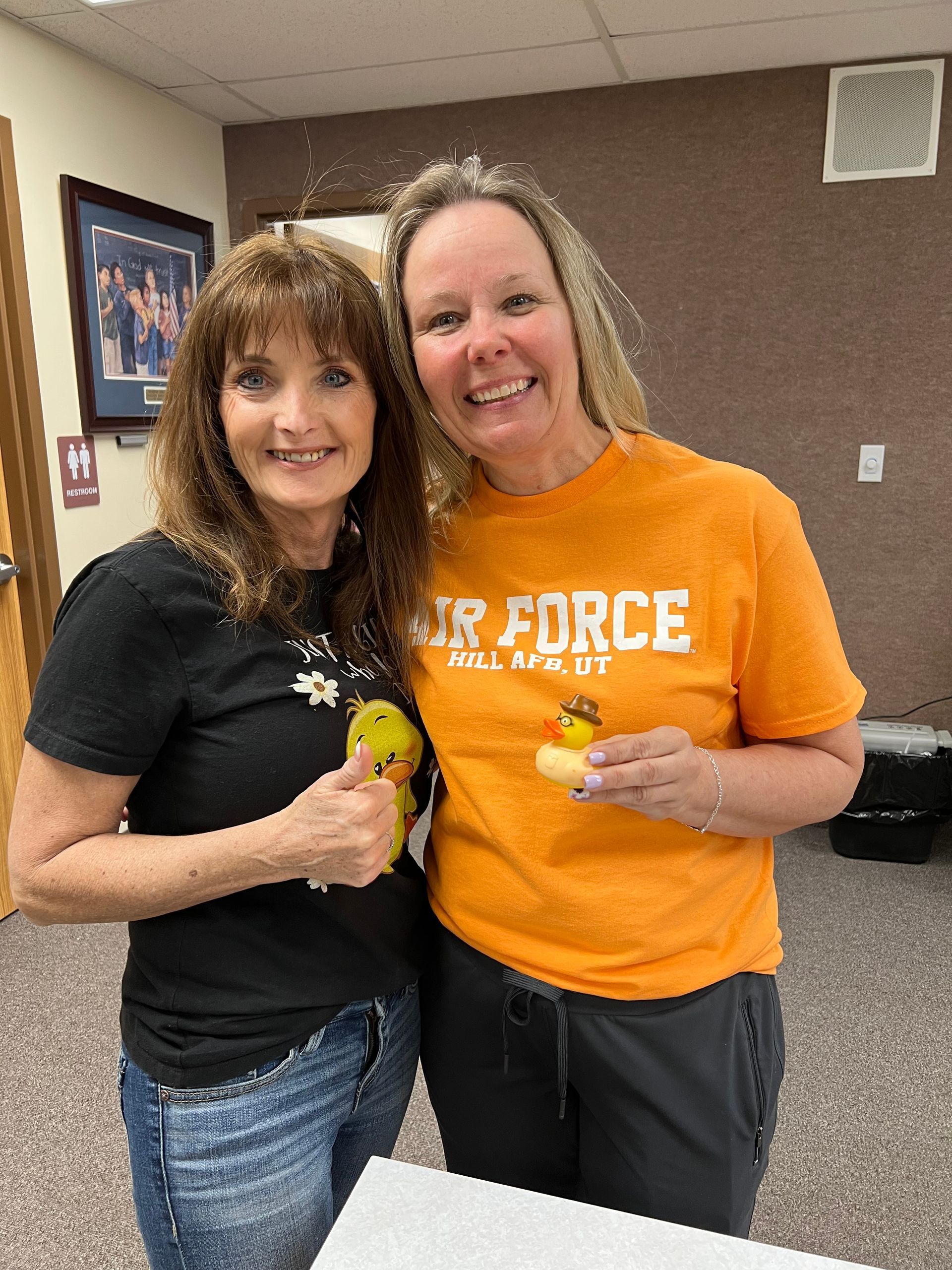 Two women are posing for a picture and one of them is wearing an air force shirt.