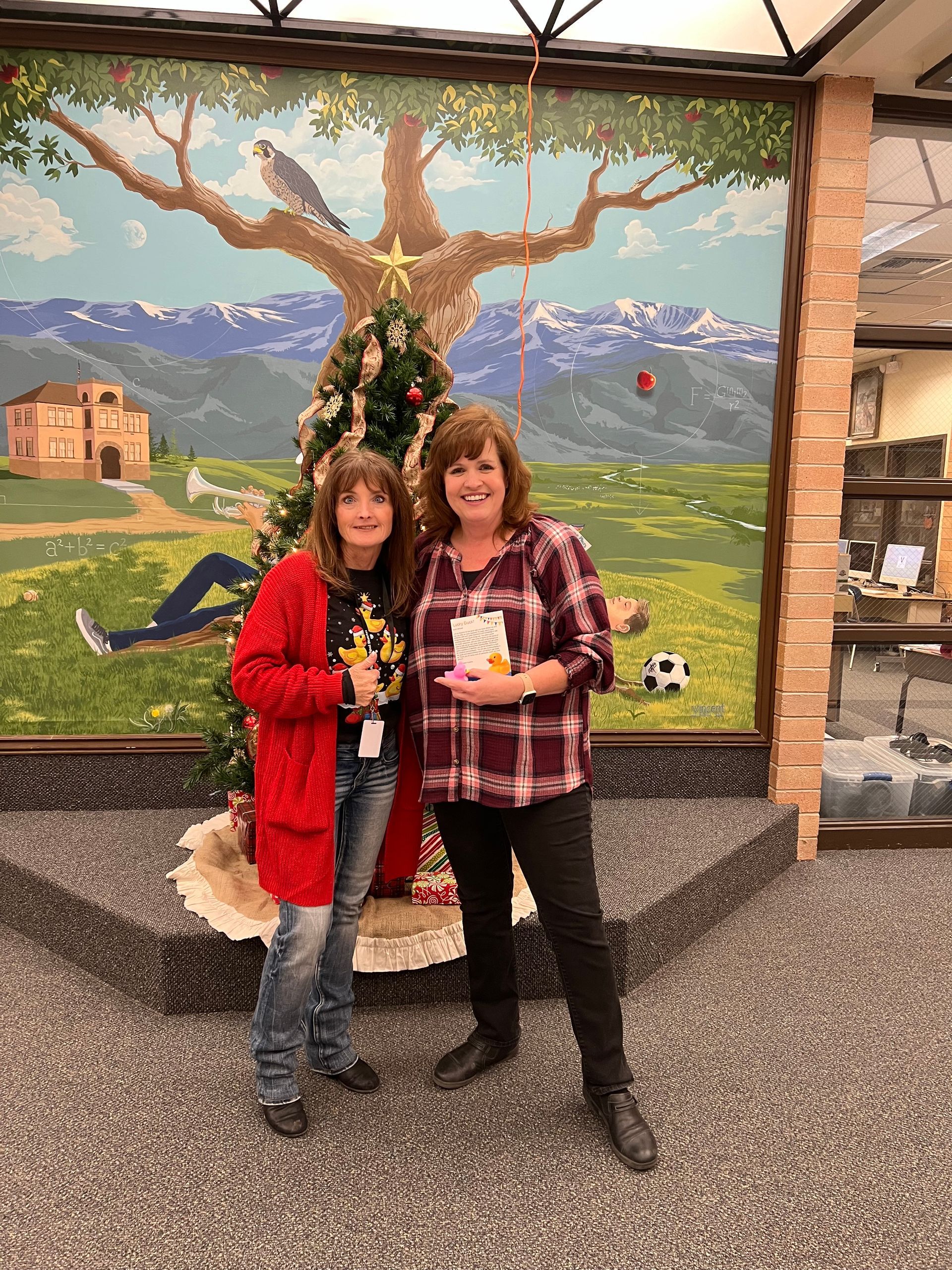 Two women are posing for a picture in front of a christmas tree.