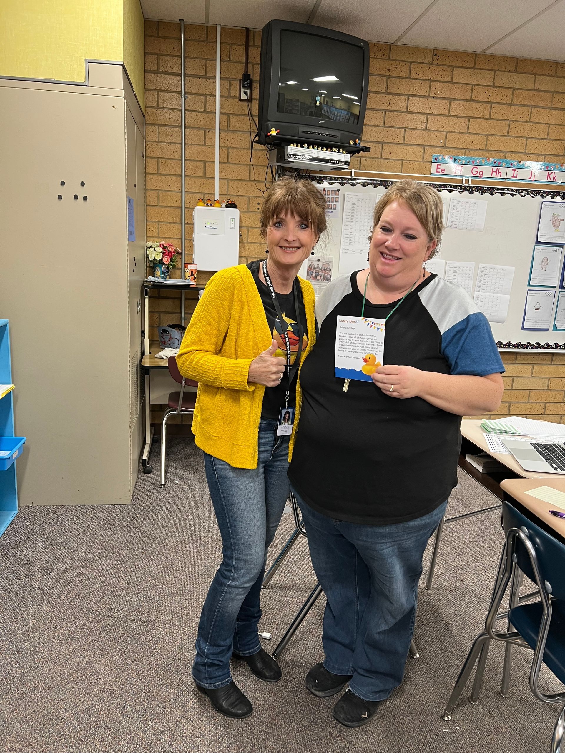 Two women are standing next to each other in a classroom.