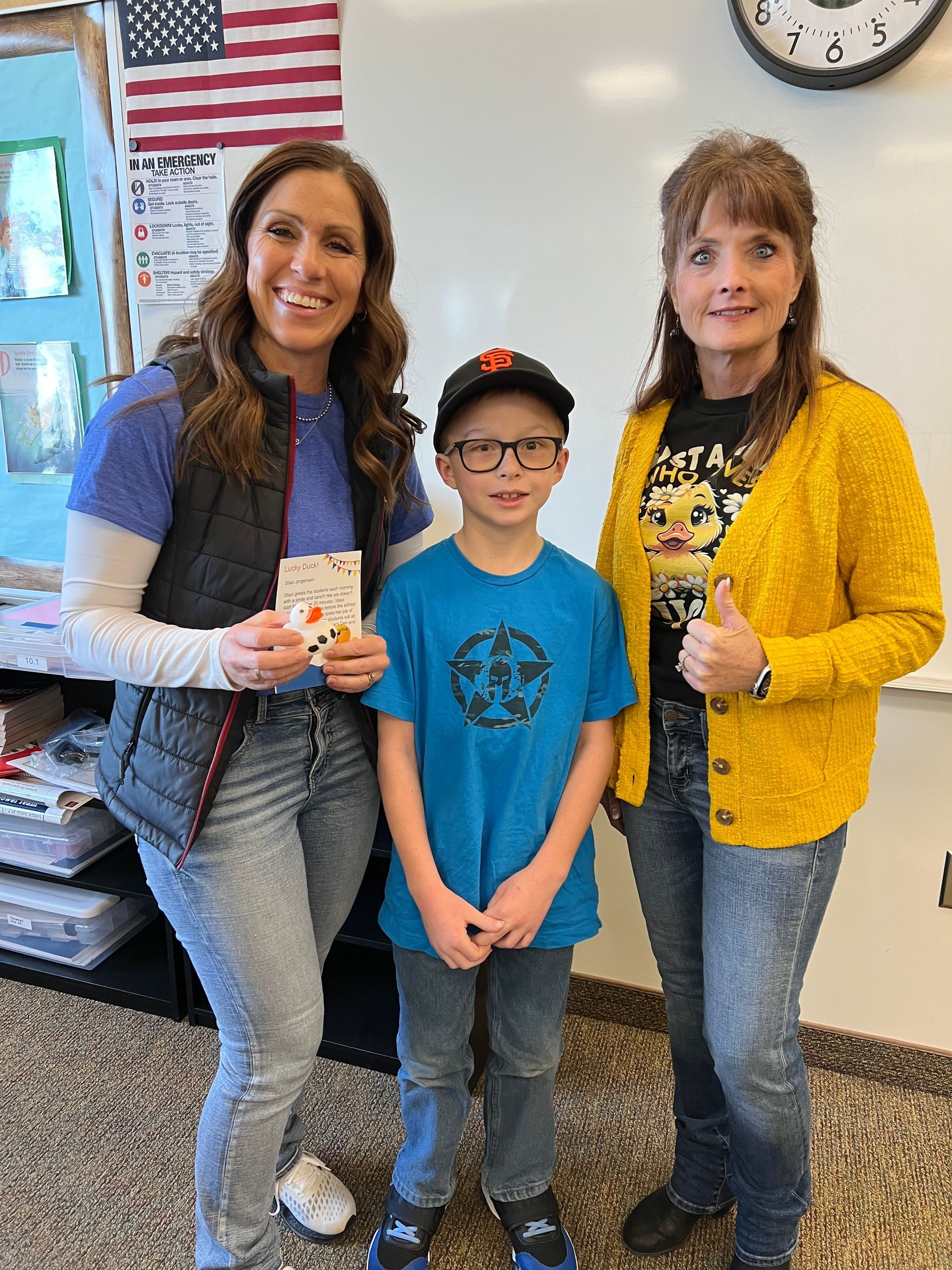 Two women and a boy are posing for a picture in a classroom.