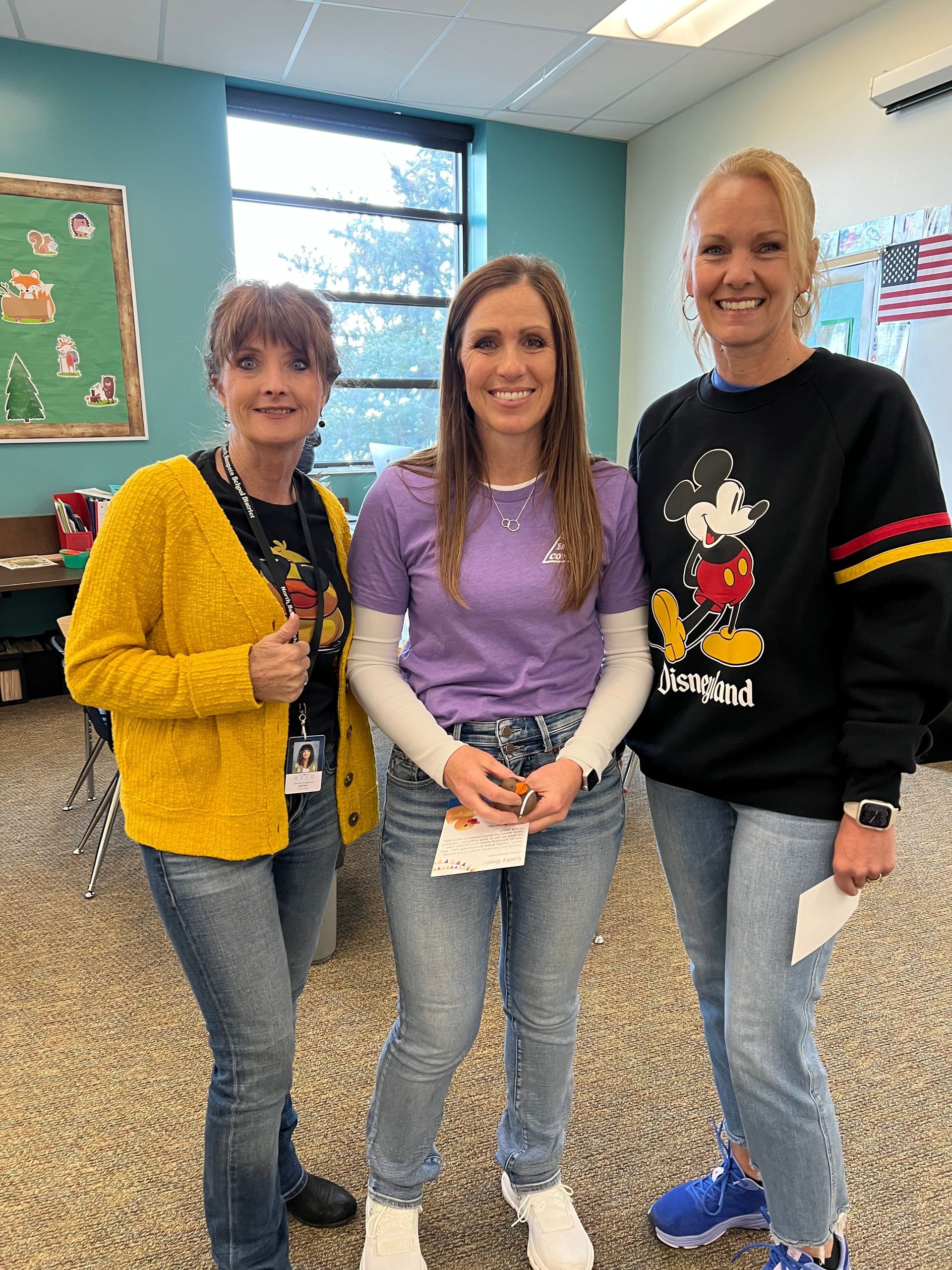 Three women are standing next to each other in a room.