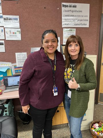 Two women are standing next to each other in an office.