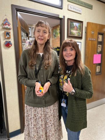 Two women are standing next to each other in a hallway.