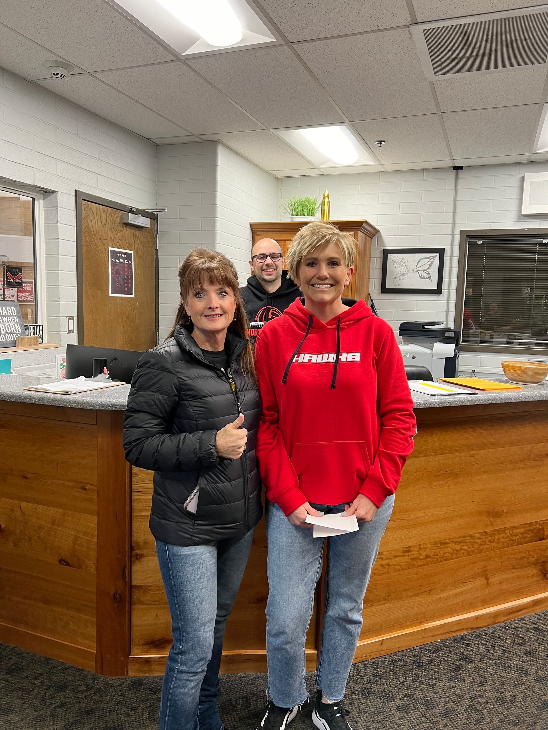 Two women are standing next to each other in front of a wooden counter.