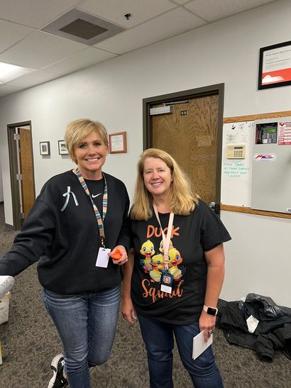 Two women are standing next to each other in a hallway.