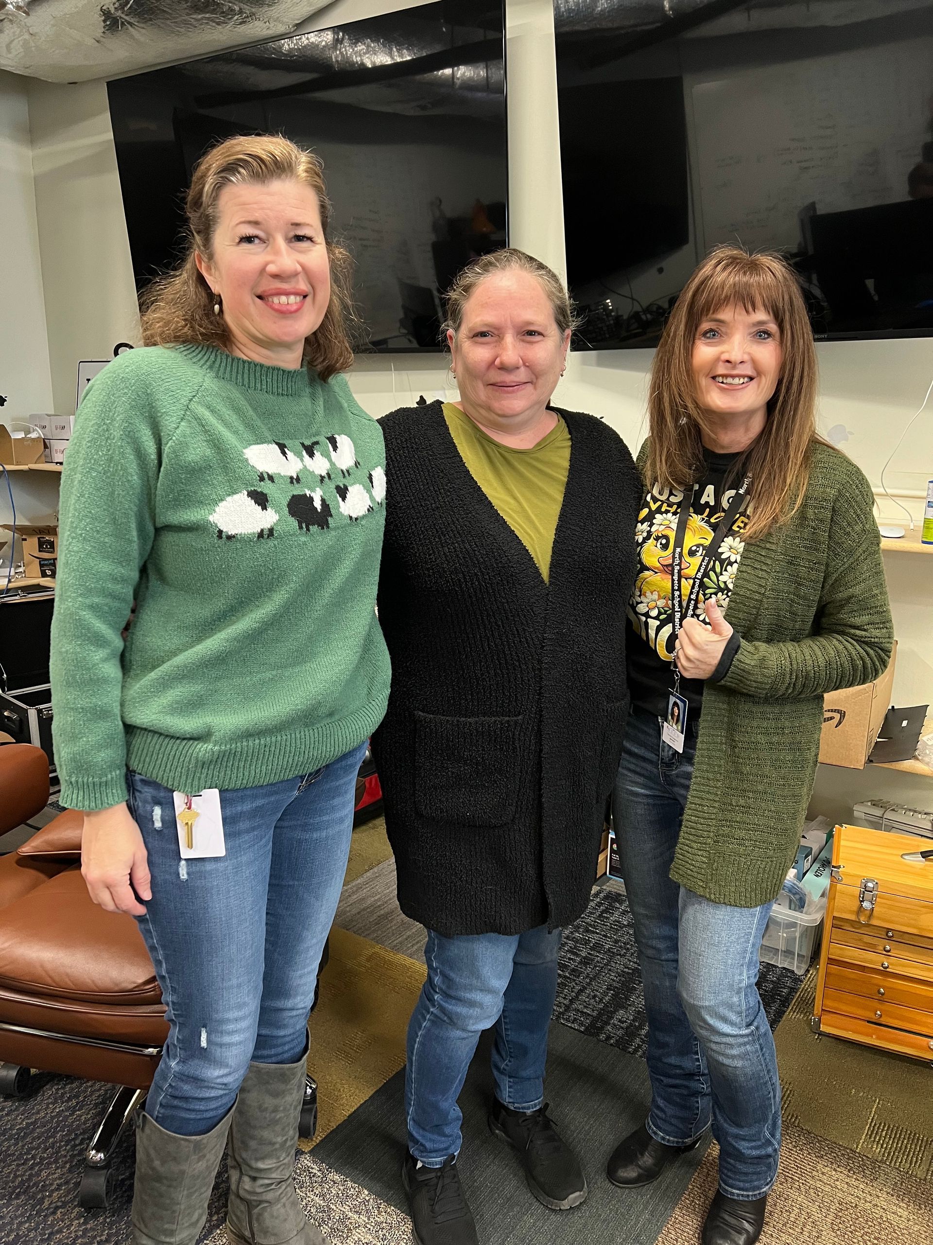 Three women are posing for a picture together in a room.