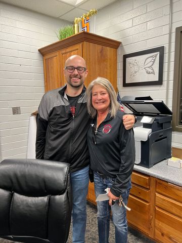 A man and a woman are posing for a picture in an office.