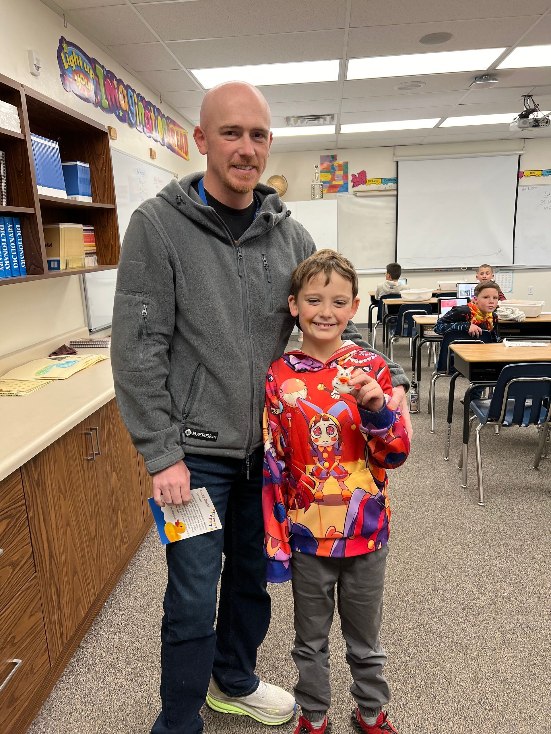 A man and a boy are posing for a picture in a classroom.