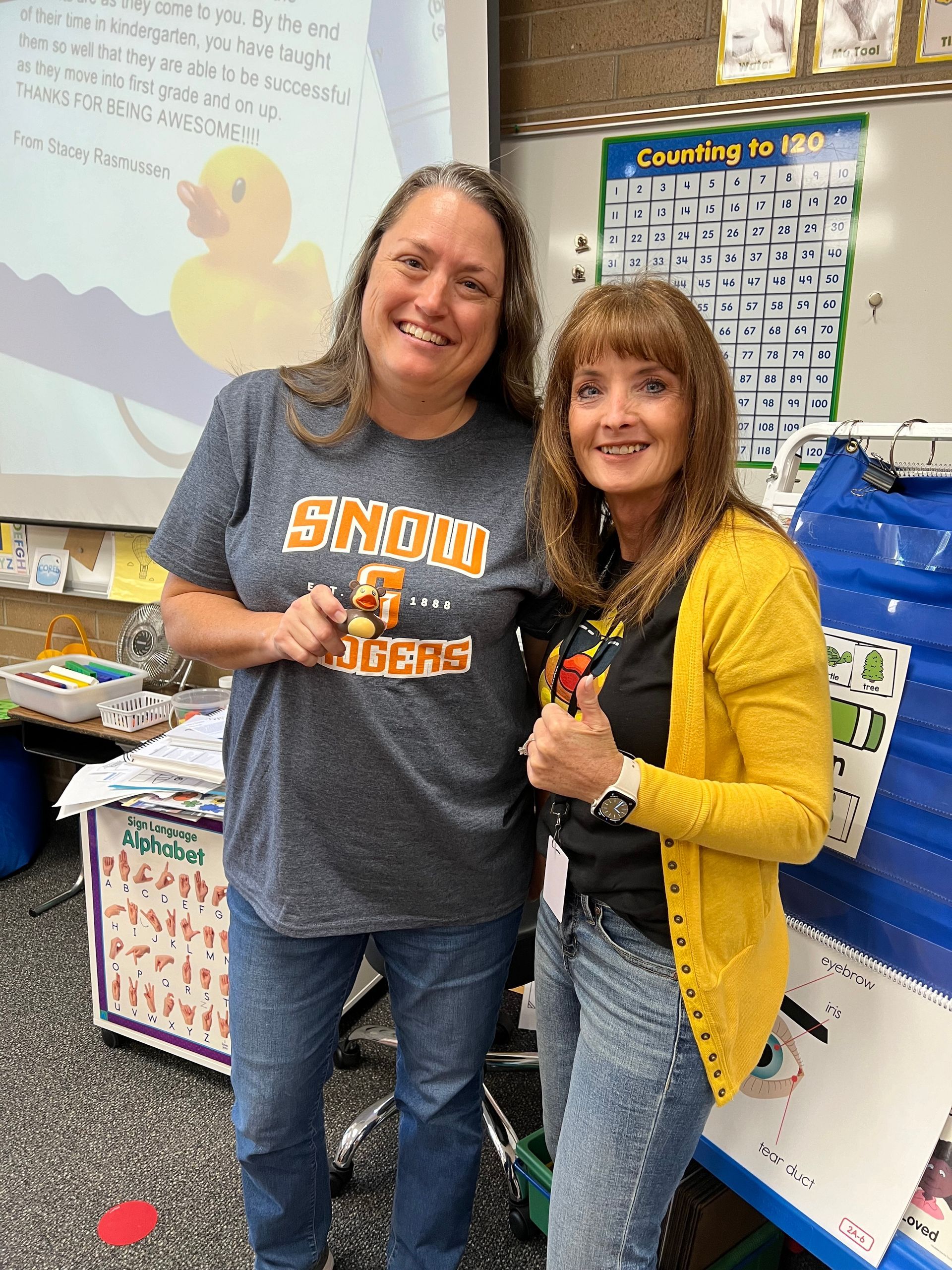 Two women are standing next to each other in a classroom.