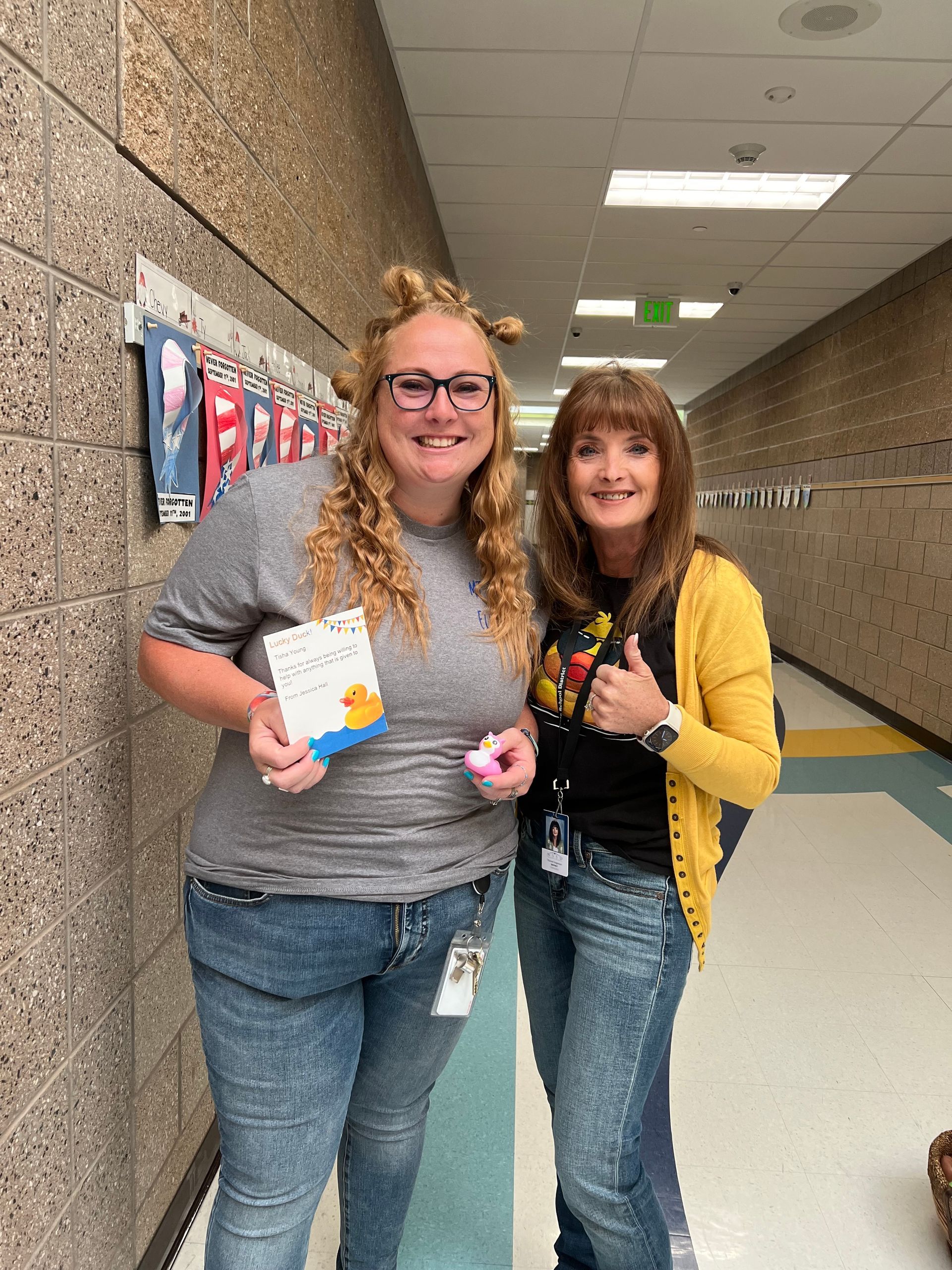 Two women are standing next to each other in a hallway.