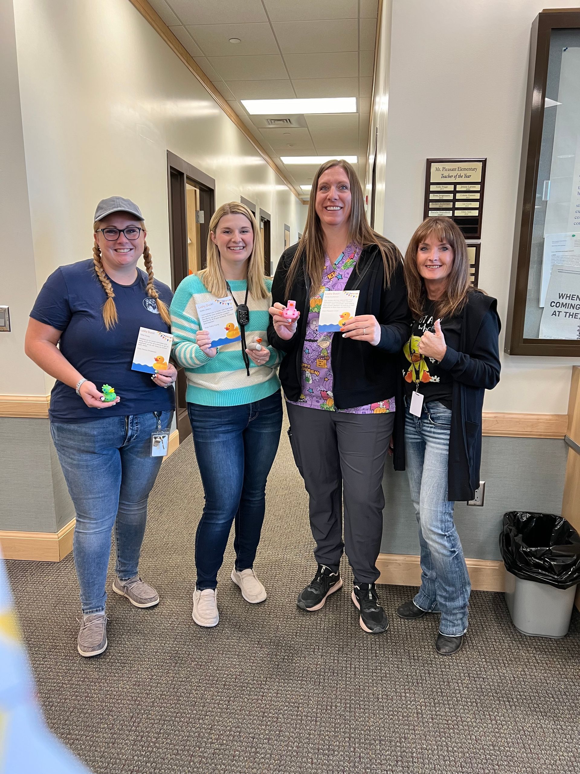 A group of women are standing in a hallway holding cards.