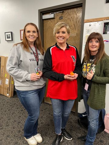 Three women are standing next to each other in a room.