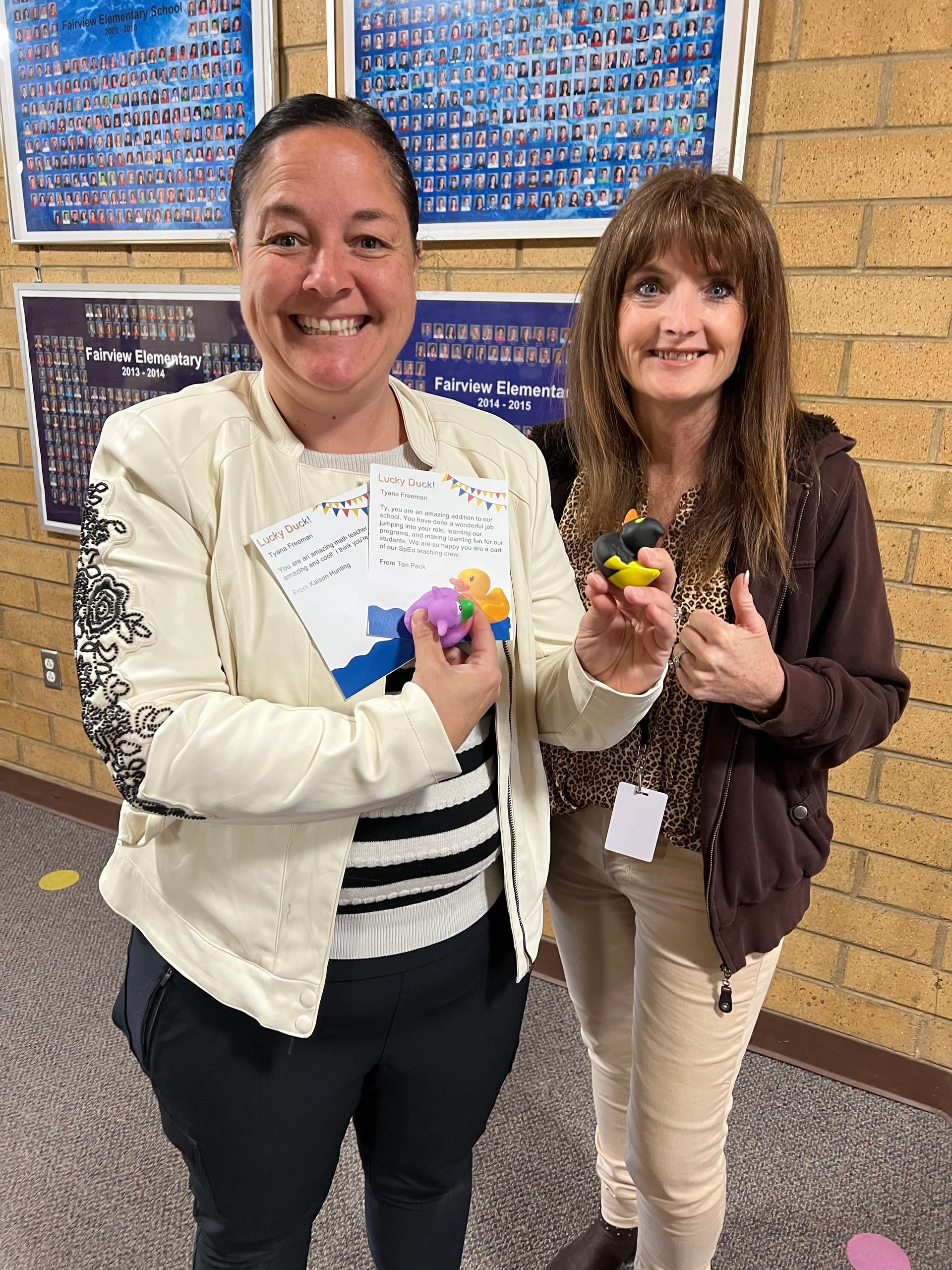 Two women are standing next to each other holding toys and smiling.