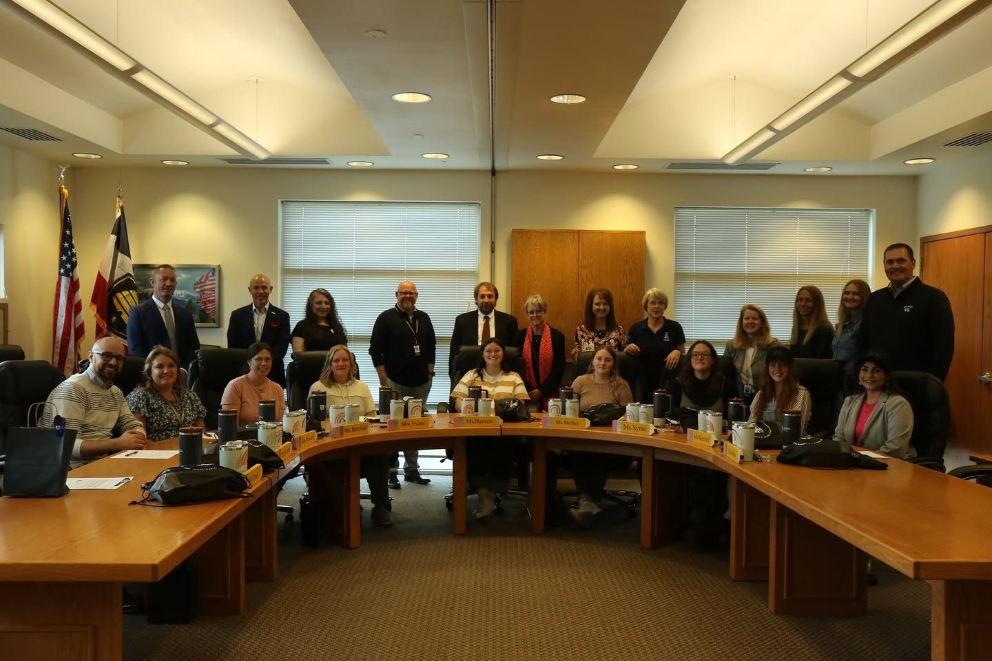 Group of people in a conference room seated around a large table.