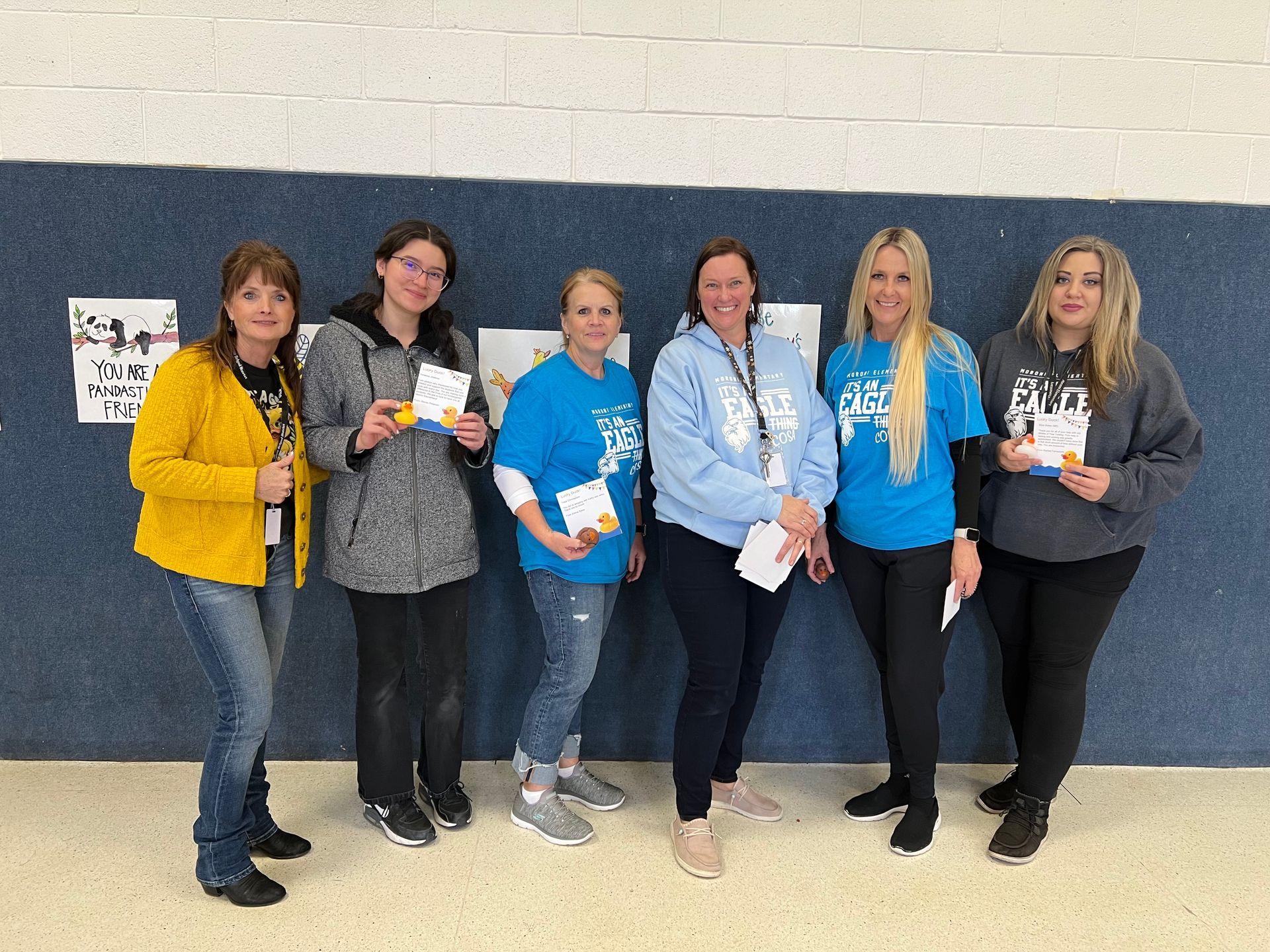 A group of women are standing next to each other in front of a blue wall.